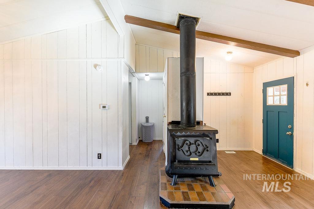 Detailed view of a wood stove, beam ceiling, wood finished floors, and wooden walls