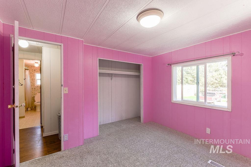 Unfurnished bedroom featuring carpet flooring, a closet, and wooden walls