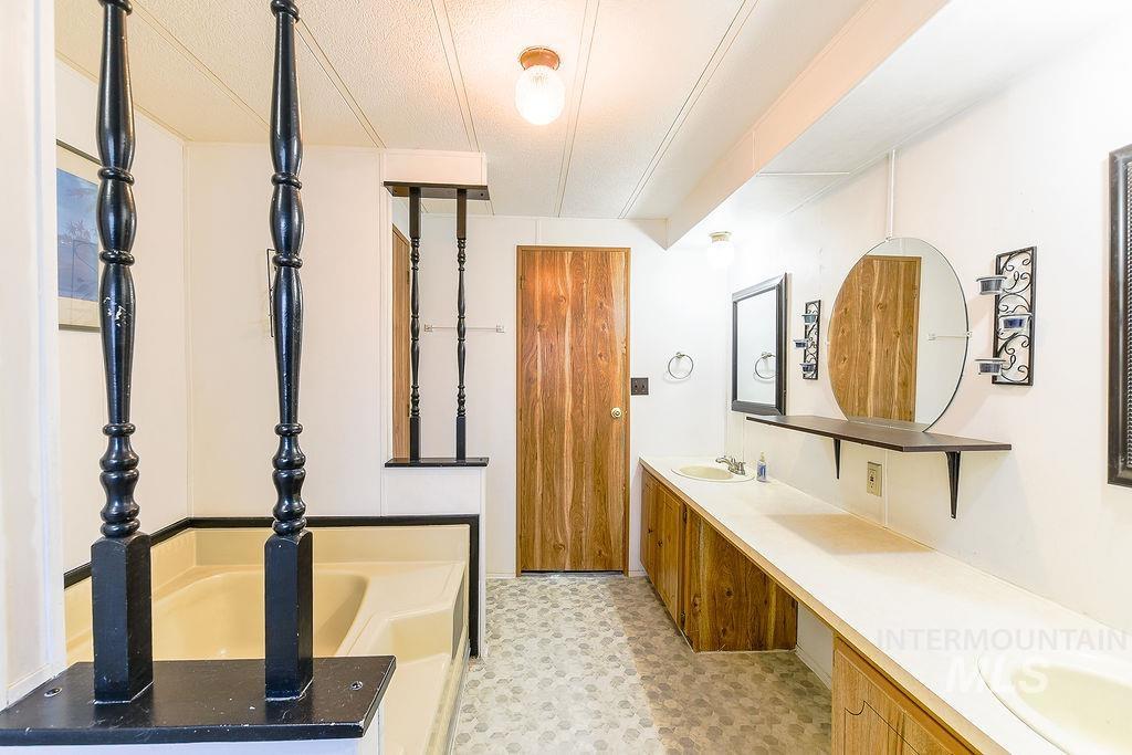 Full bath with double vanity, a bath, and light floors