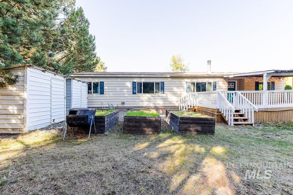 Back of property featuring a vegetable garden, a deck, a yard, and a storage unit