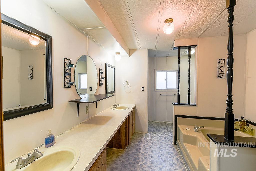 Bathroom with double vanity, a bath, and a textured ceiling