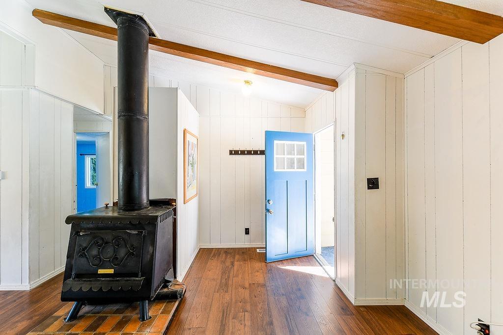 Entrance foyer featuring beam ceiling, wood walls, dark wood finished floors, and a wood stove