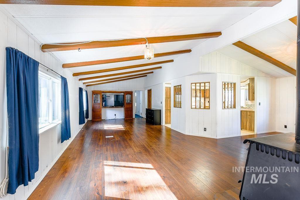 Unfurnished living room with dark wood-style flooring, a wood stove, and wood walls