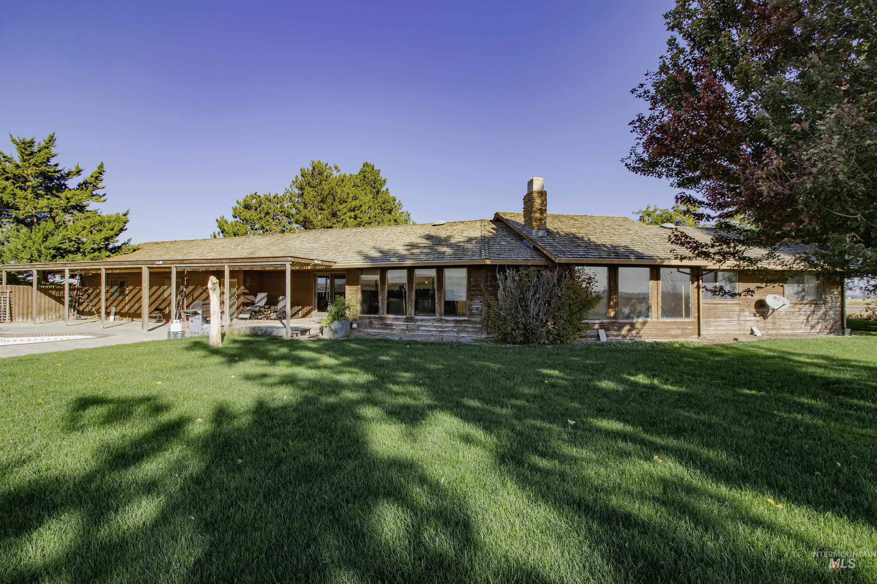 View of back facade featuring a front lawn, a patio, and a chimney