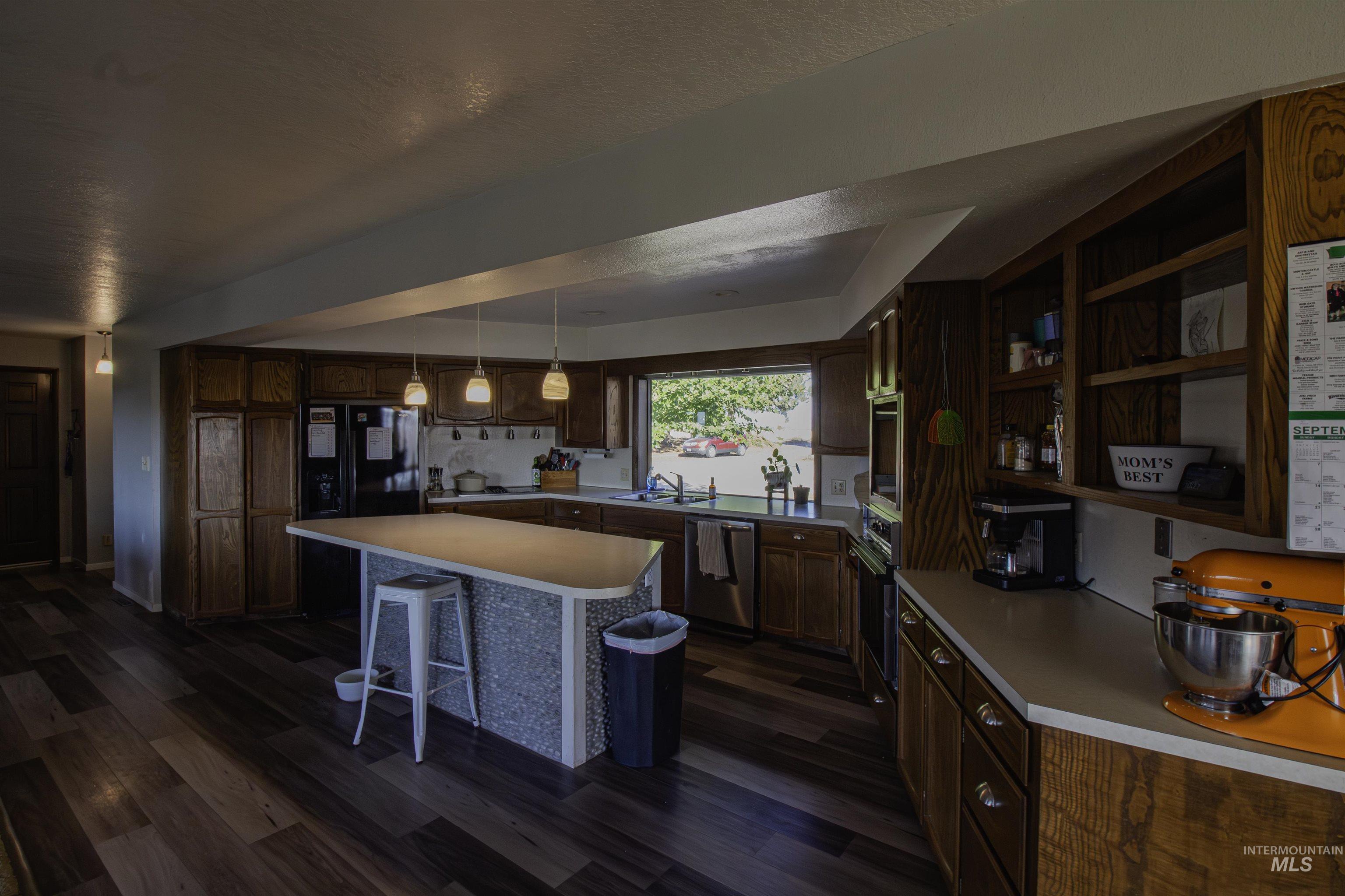 Kitchen with a breakfast bar, dark wood-type flooring, open shelves, a center island, and light countertops