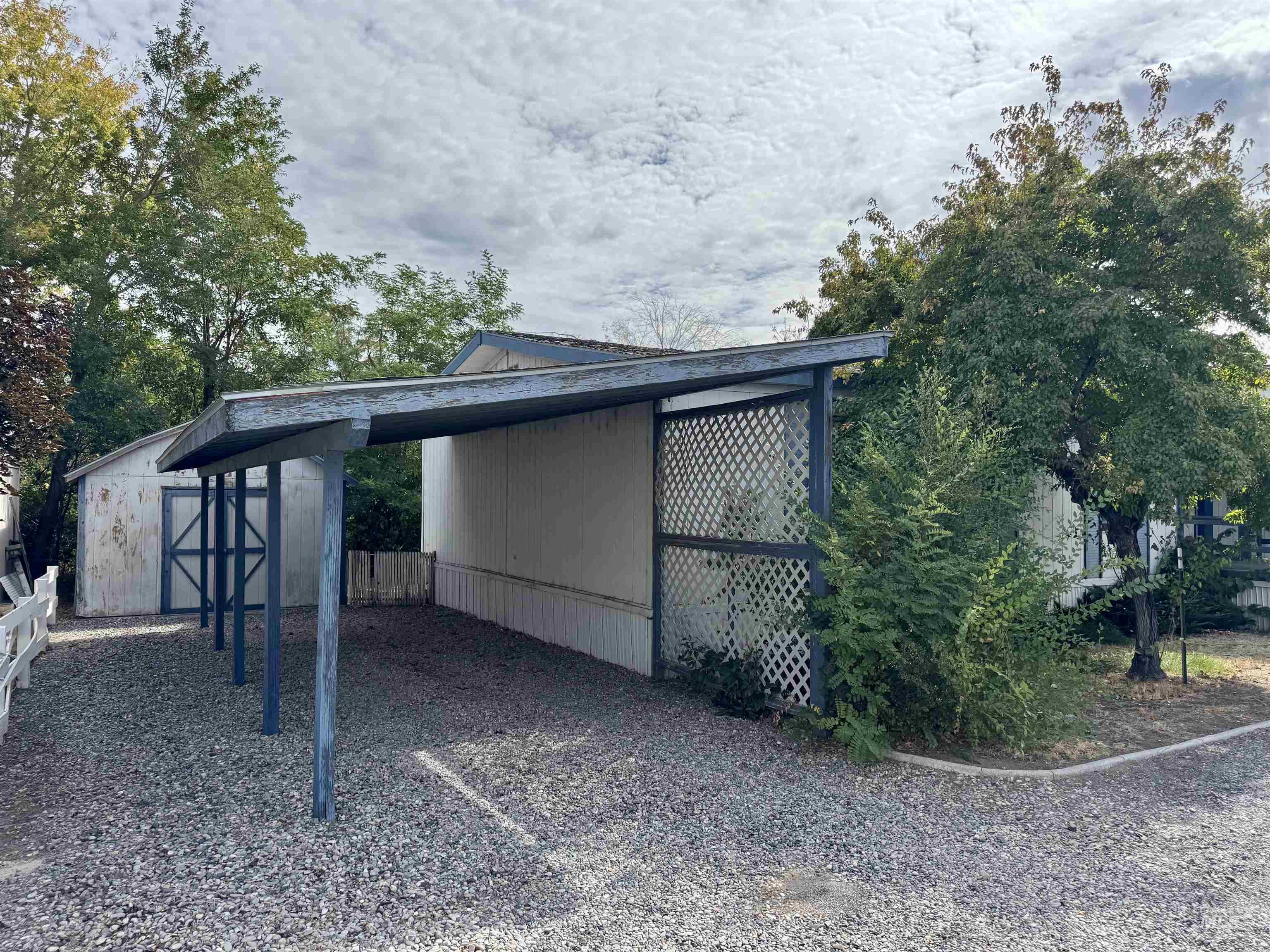 View of parking / parking lot with a storage shed and gravel driveway