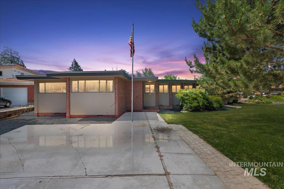 View of front of home featuring a lawn, crawl space, and brick siding