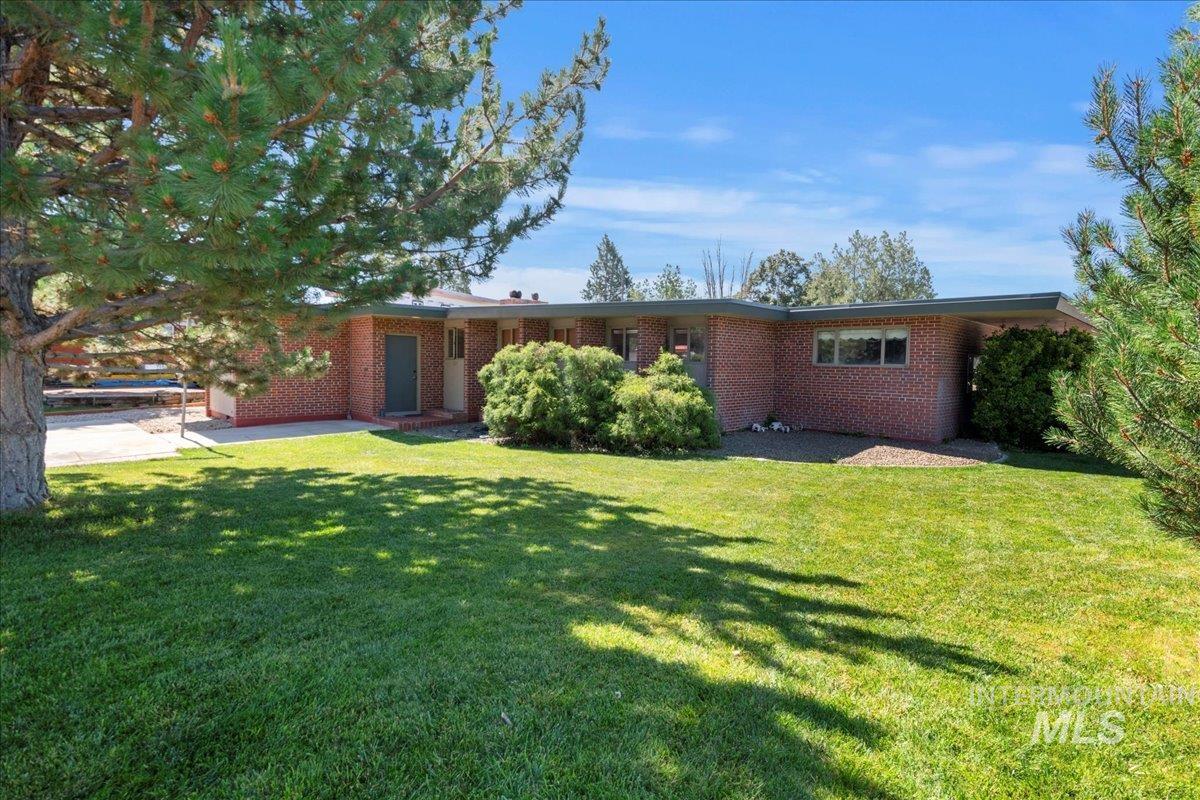 Rear view of house featuring a yard, brick siding, and a patio area