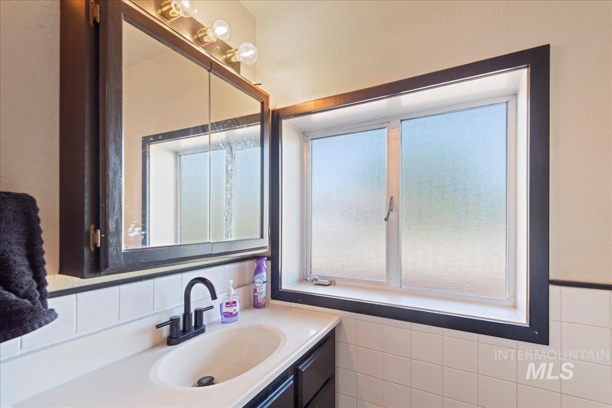 Bathroom featuring vanity, healthy amount of natural light, and tile walls