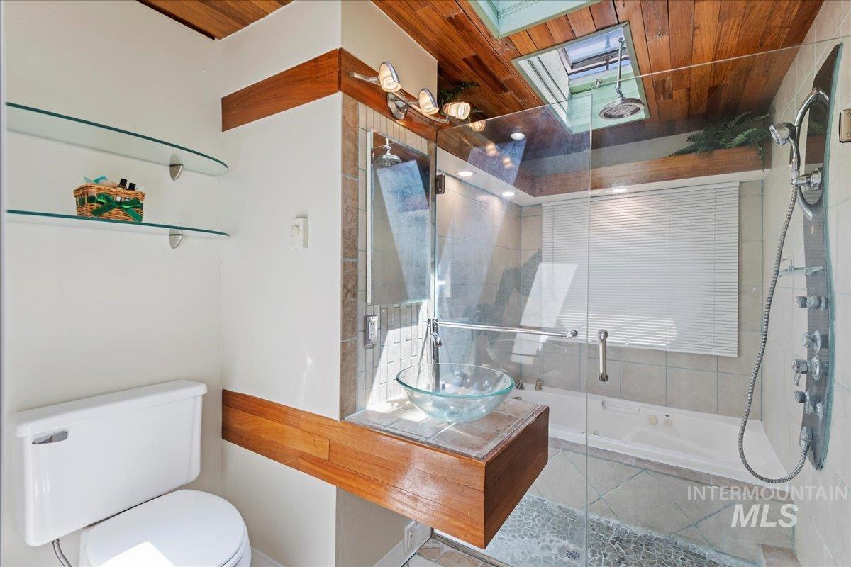 Bathroom featuring tiled shower / bath, wooden ceiling, vanity, and a skylight