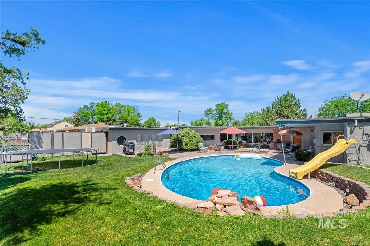 Outdoor pool with a trampoline, a patio, and a yard