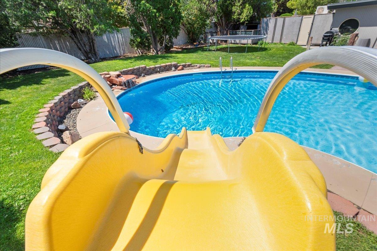 View of swimming pool featuring a fenced backyard, a trampoline, and a patio