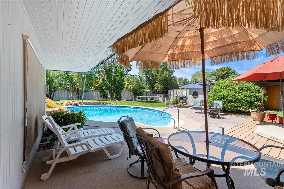 View of swimming pool featuring a patio, a fenced backyard, and outdoor dining space