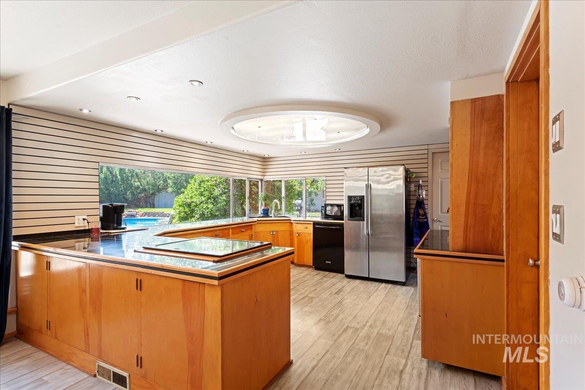 Kitchen featuring black appliances, light wood finished floors, brown cabinets, a peninsula, and recessed lighting