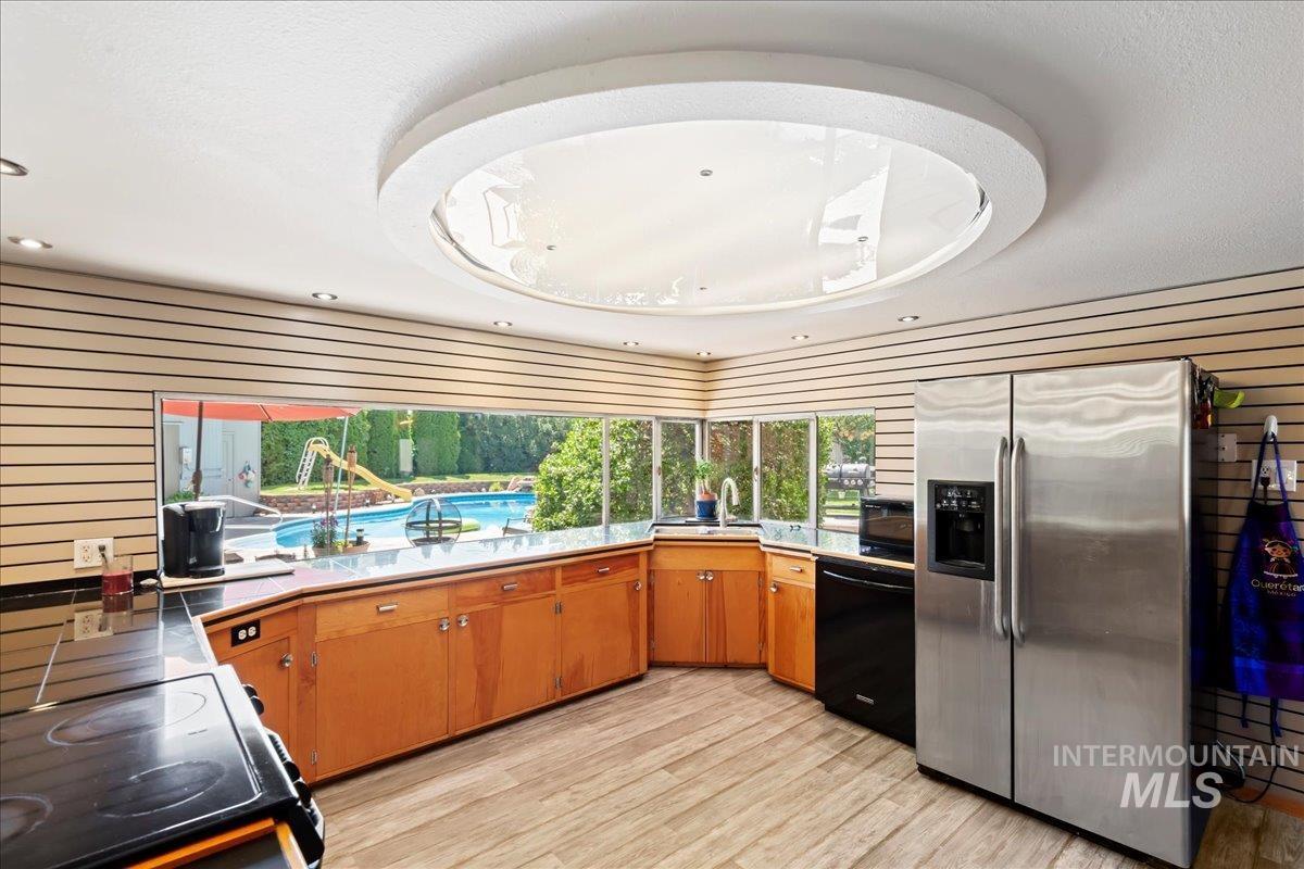 Kitchen with wooden walls, stainless steel fridge with ice dispenser, range with electric stovetop, light countertops, and dishwasher