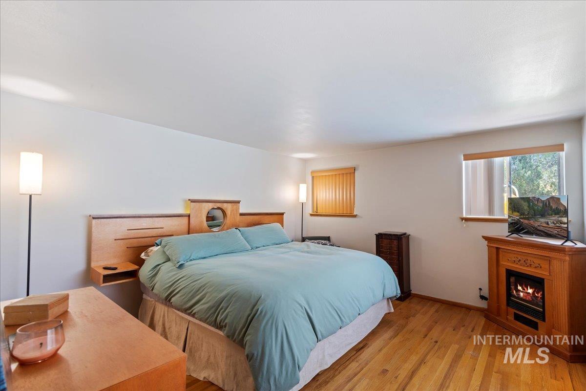 Bedroom featuring light wood-type flooring and a lit fireplace
