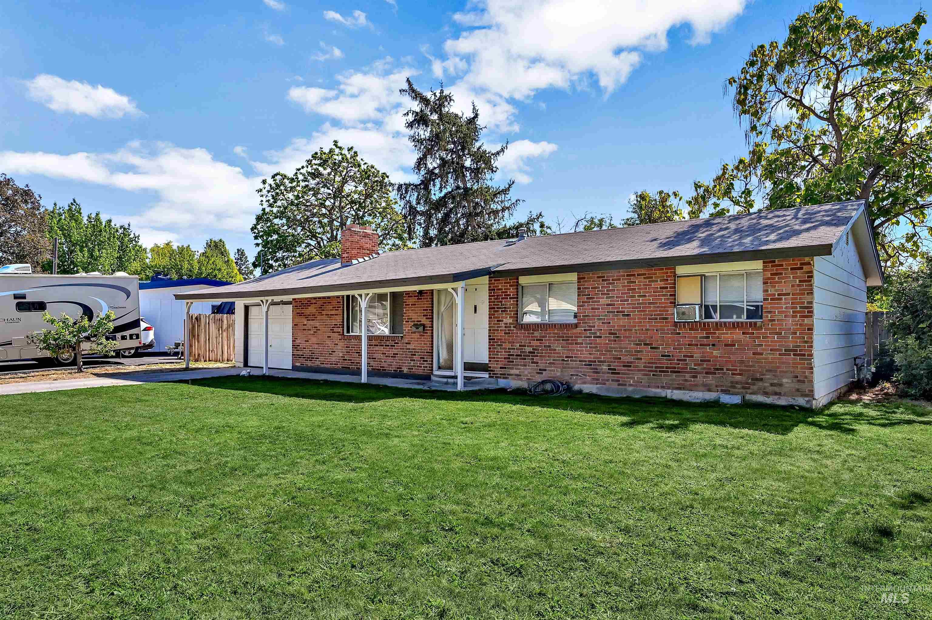Single story home with a front lawn, a garage, brick siding, a chimney, and driveway