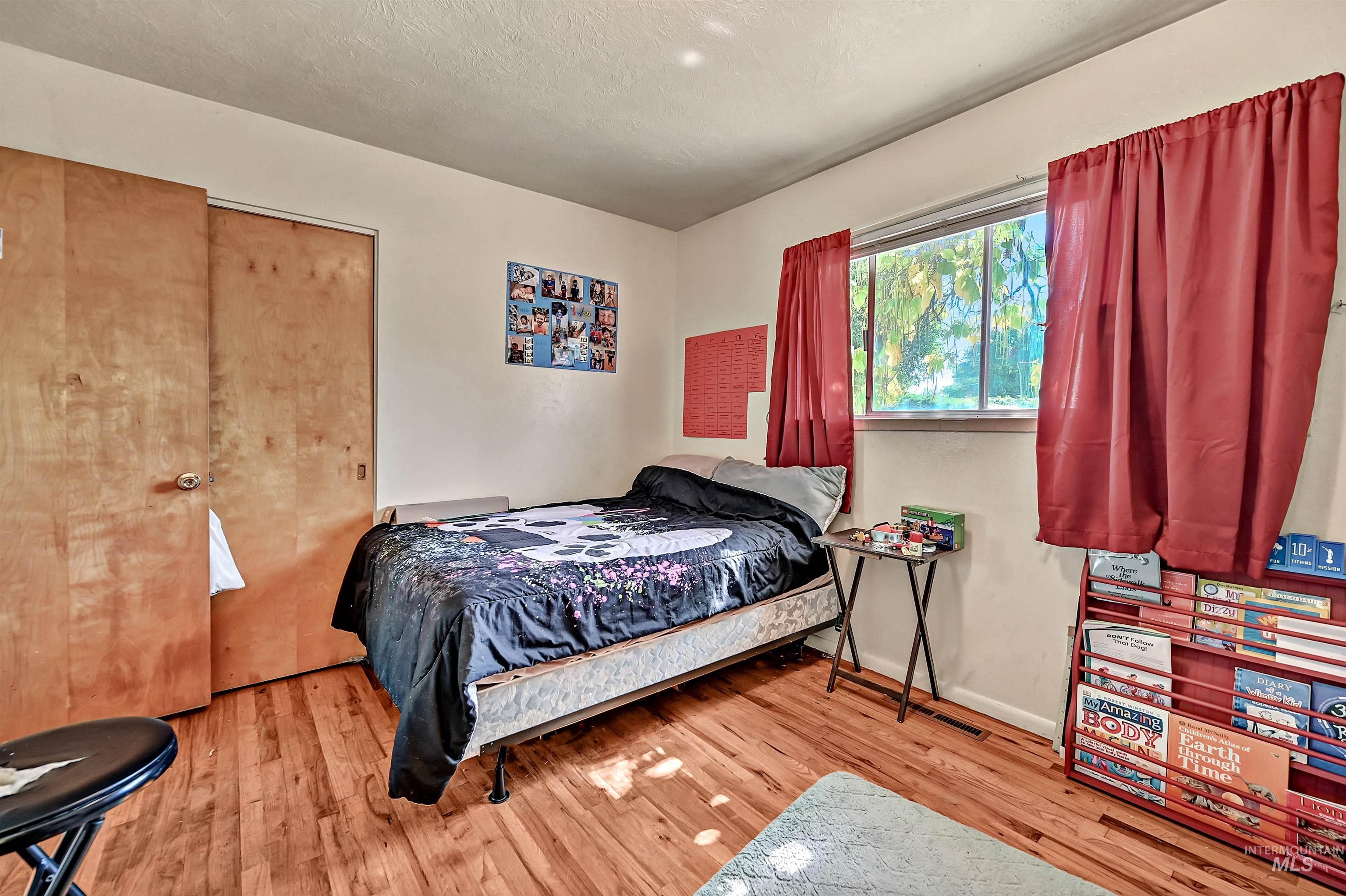 Bedroom with light wood finished floors and a textured ceiling