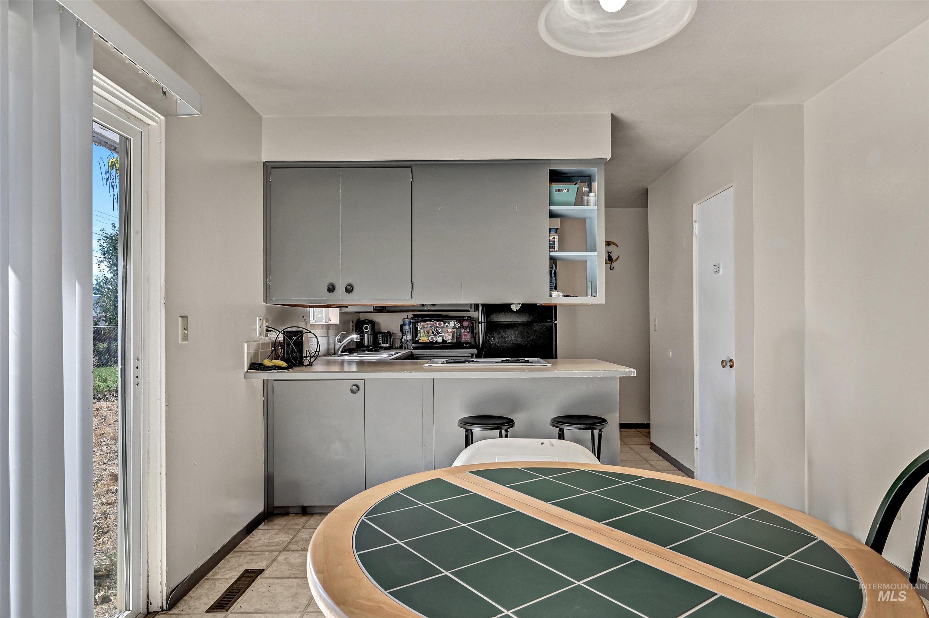 Kitchen featuring gray cabinets, open shelves, light countertops, and light tile patterned flooring