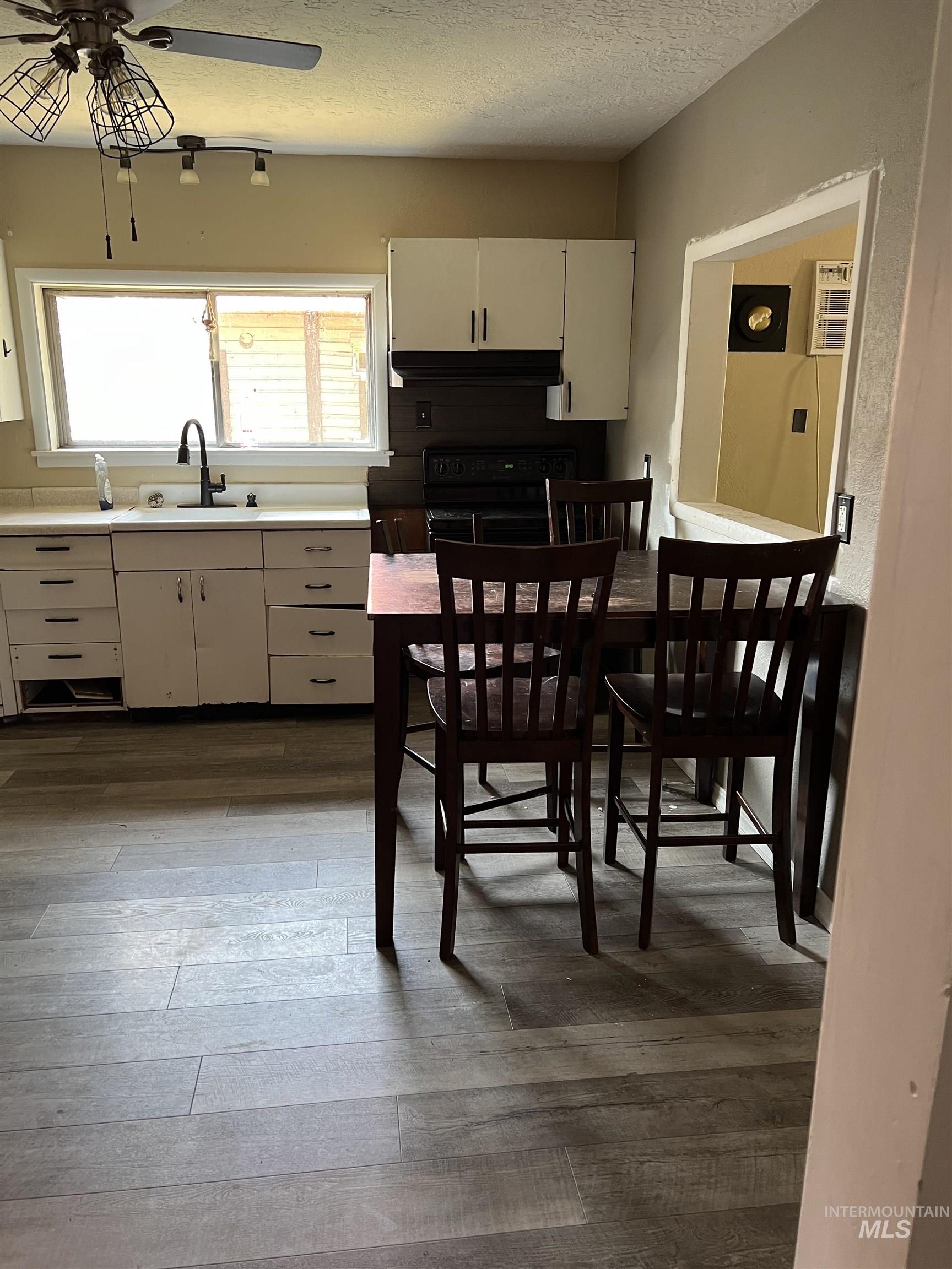 Kitchen with a ceiling fan, electric range, light countertops, dark wood-style floors, and a textured ceiling