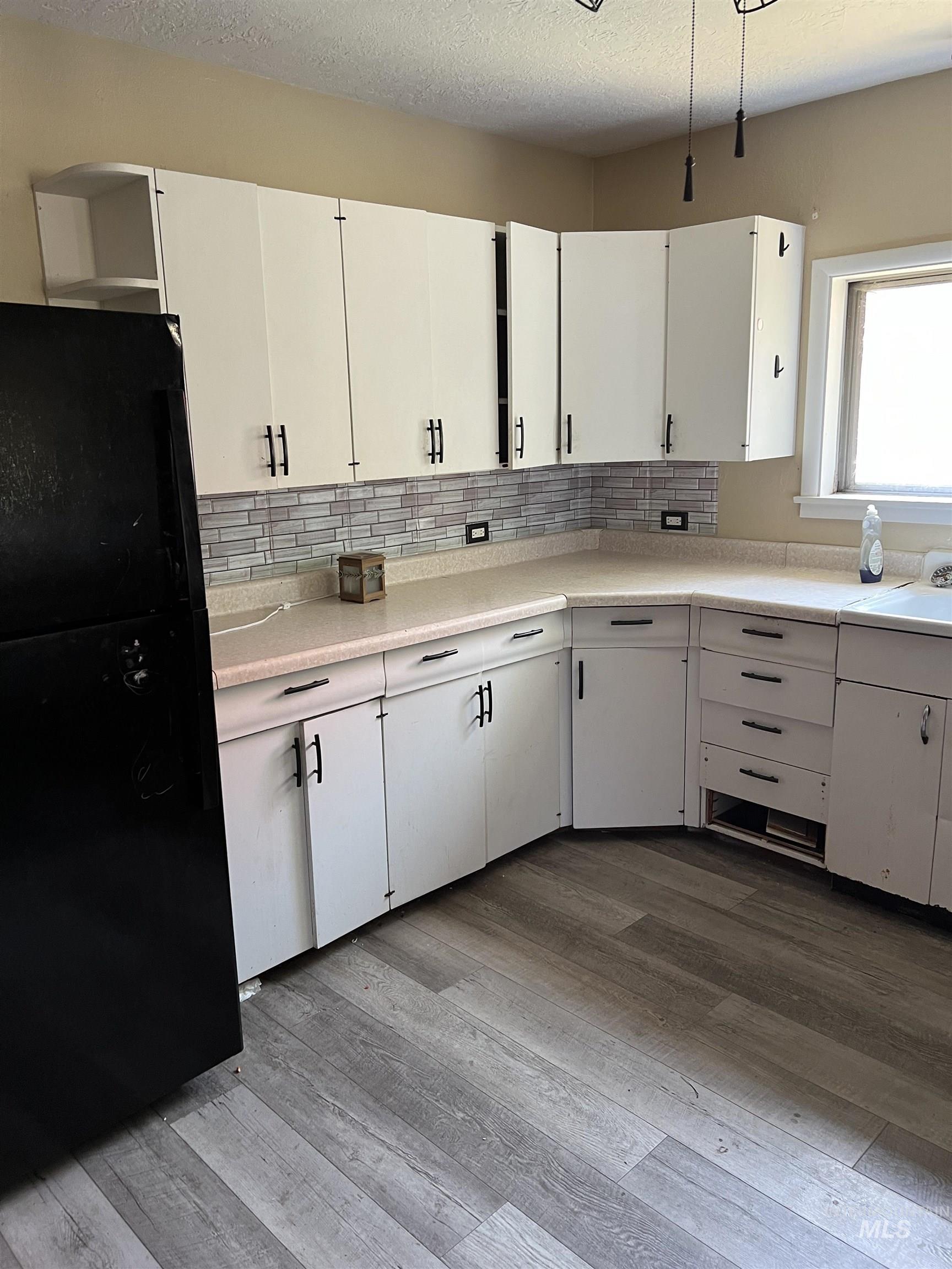 Kitchen featuring freestanding refrigerator, light wood finished floors, and backsplash