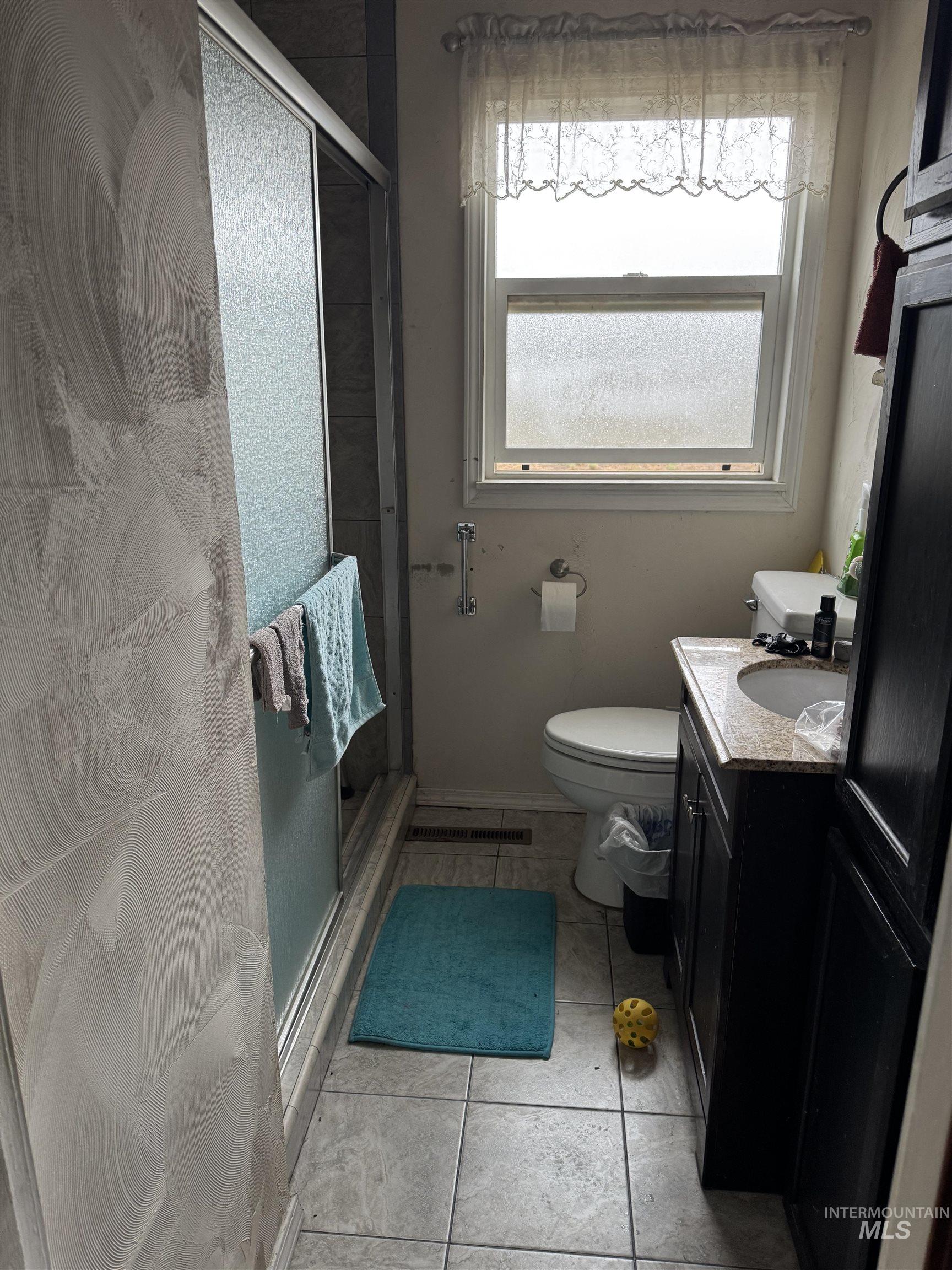 Full bathroom featuring vanity, a shower stall, and light tile patterned floors