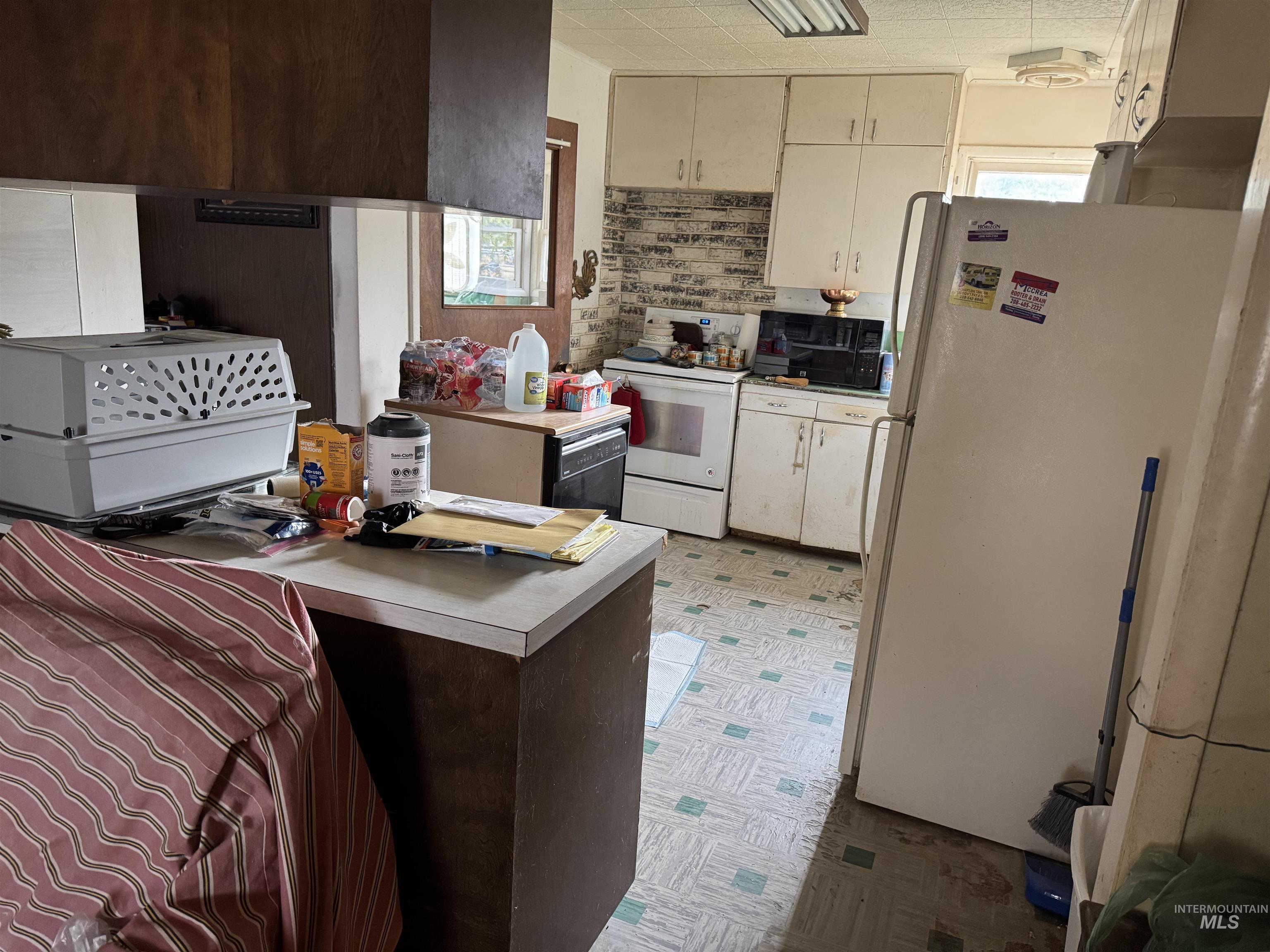 Kitchen featuring healthy amount of natural light, white appliances, light flooring, and light countertops