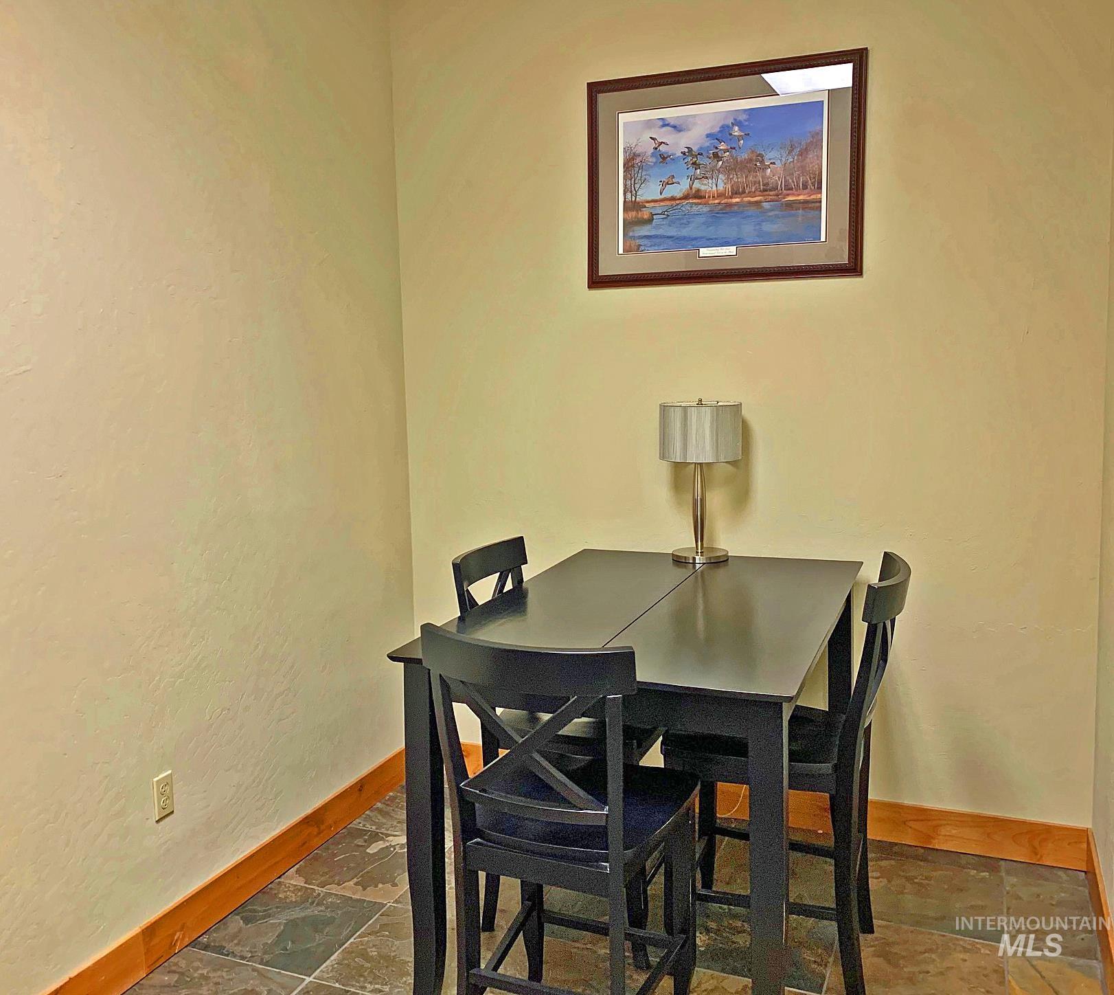 Dining room featuring a textured wall and dark stone finish floors