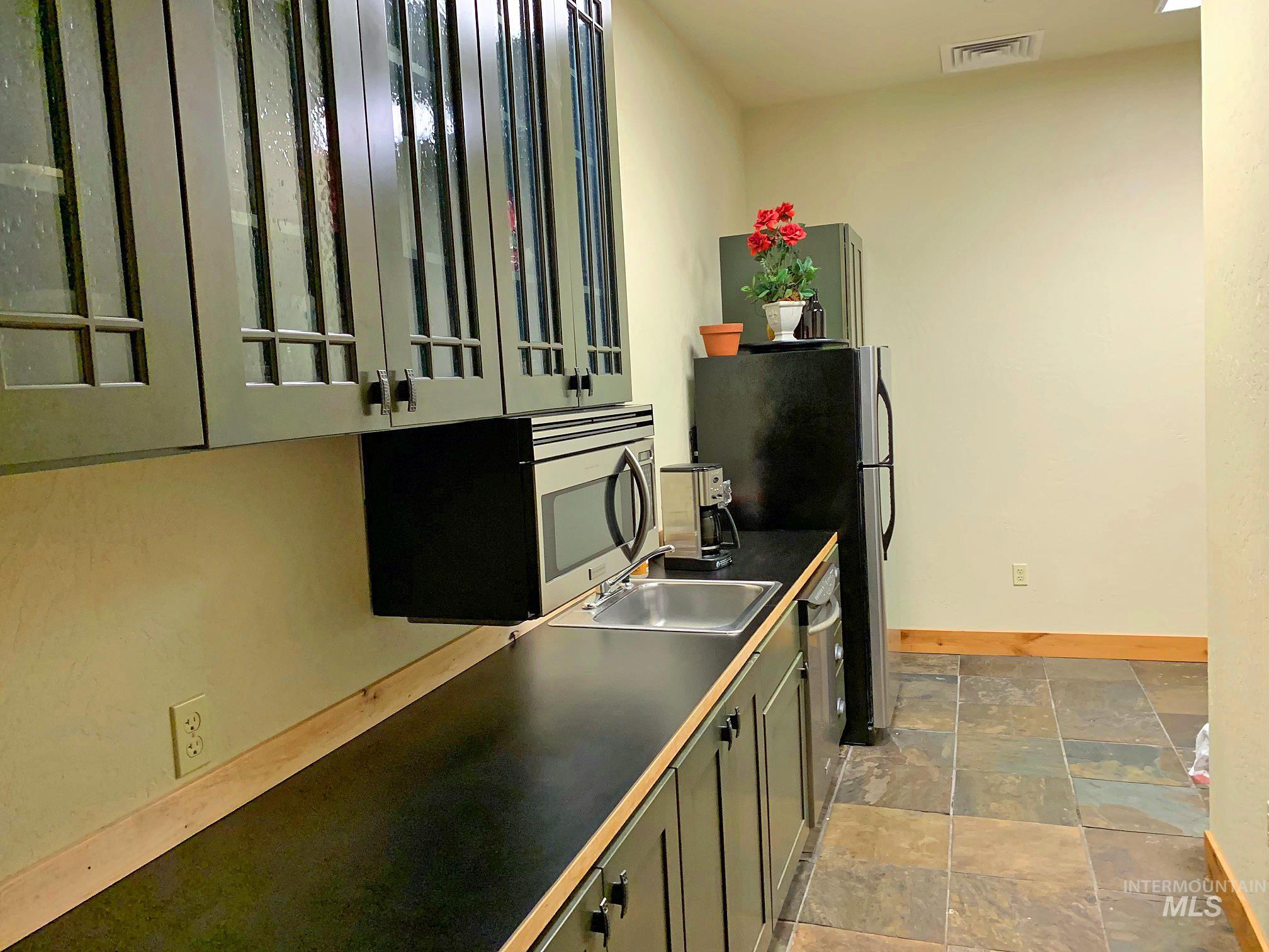 Kitchen with appliances with stainless steel finishes and light stone finish floors
