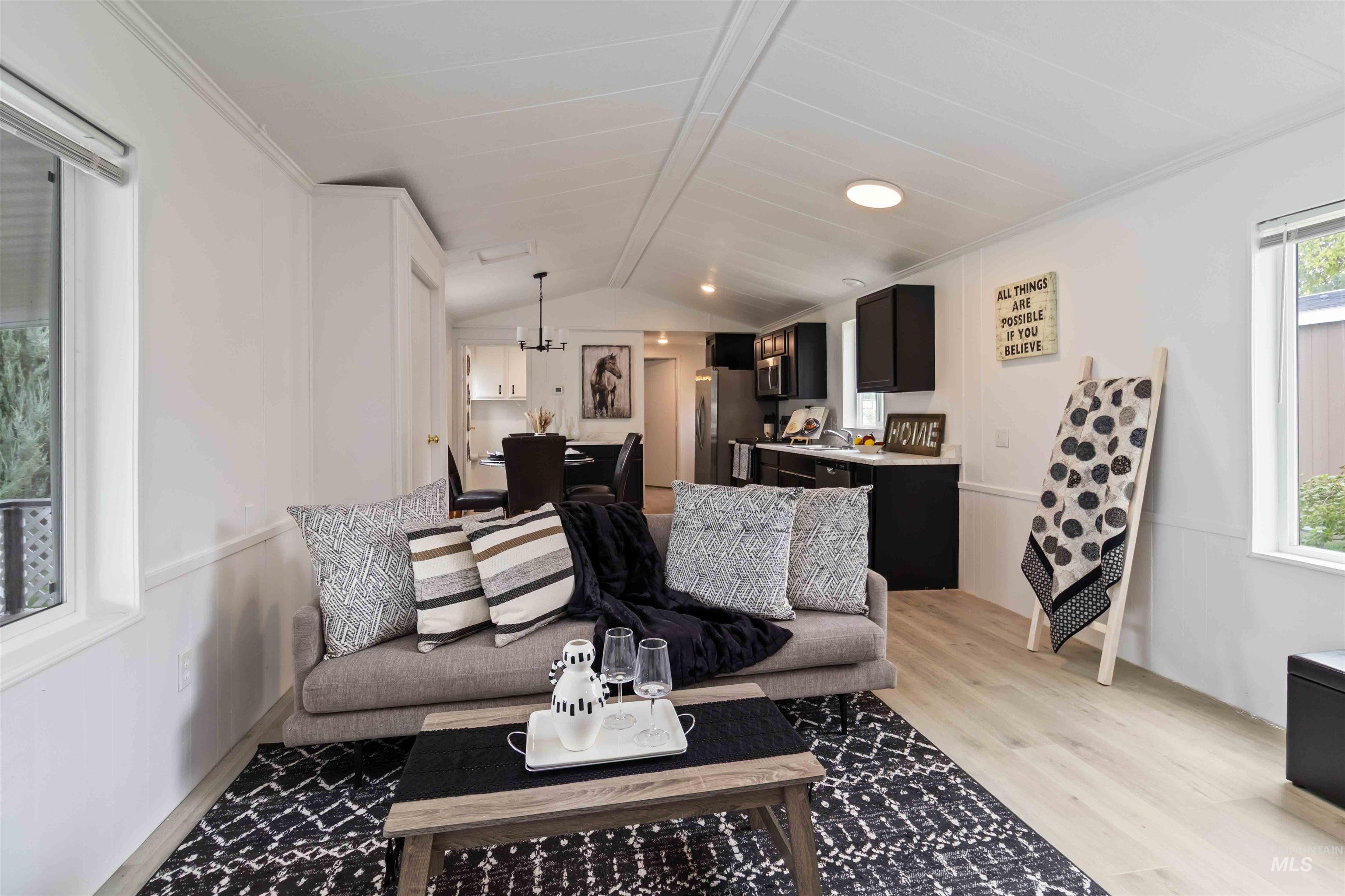 Living area featuring healthy amount of natural light, vaulted ceiling, and light wood finished floors