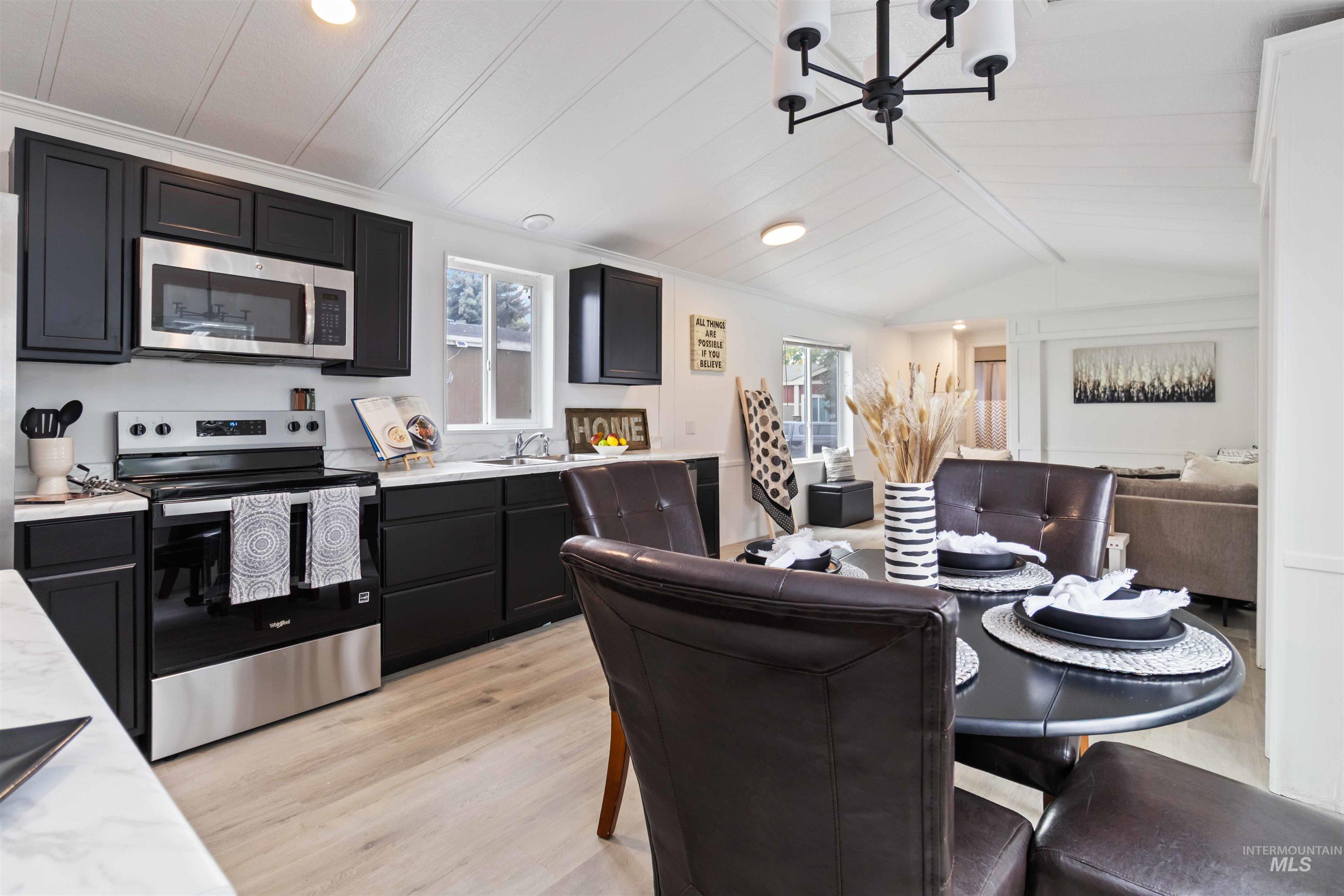Dining area featuring light wood-style flooring, a chandelier, vaulted ceiling, recessed lighting, and crown molding