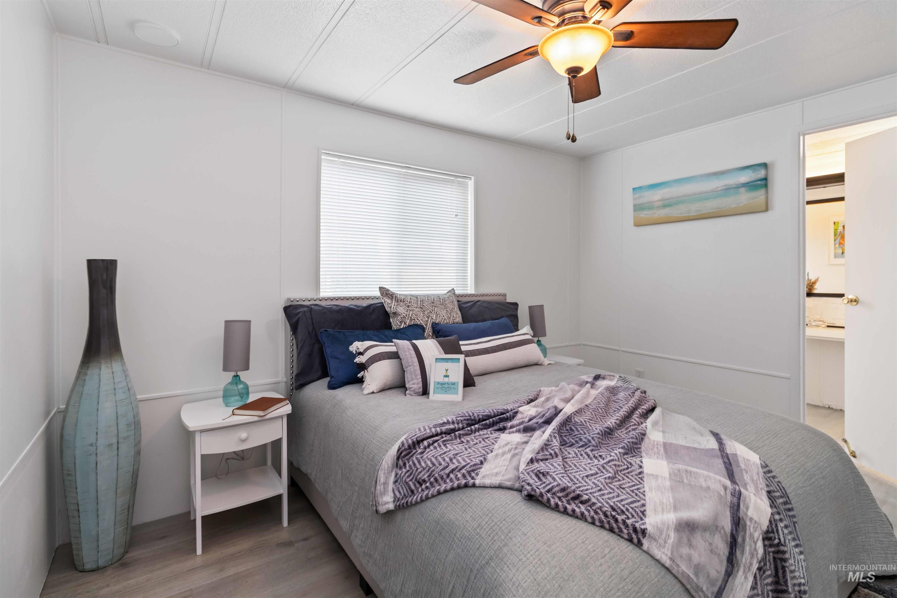 Bedroom with light wood-type flooring, a ceiling fan, and ensuite bathroom