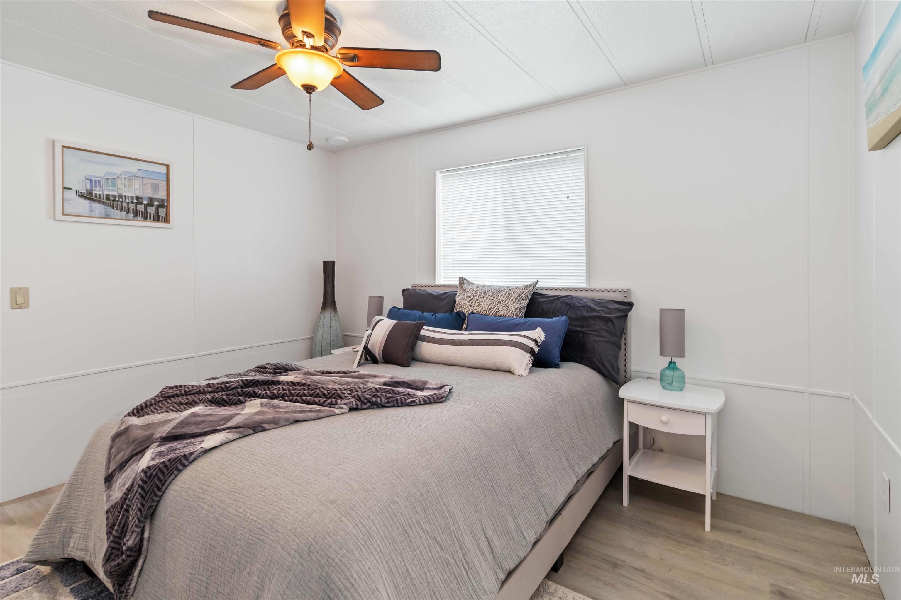 Bedroom featuring light wood finished floors, a ceiling fan, and a decorative wall