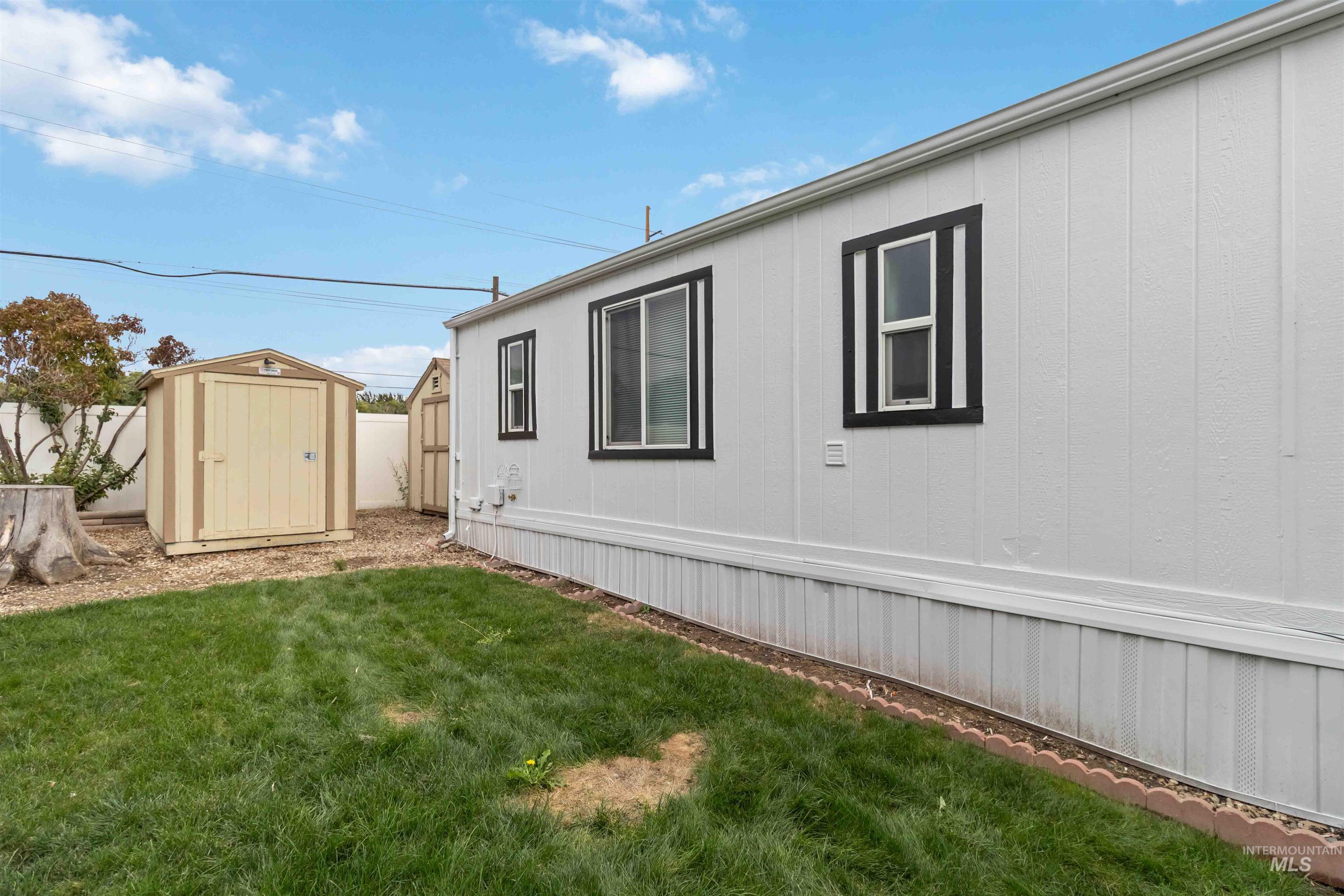 View of side of home with a yard and a storage unit
