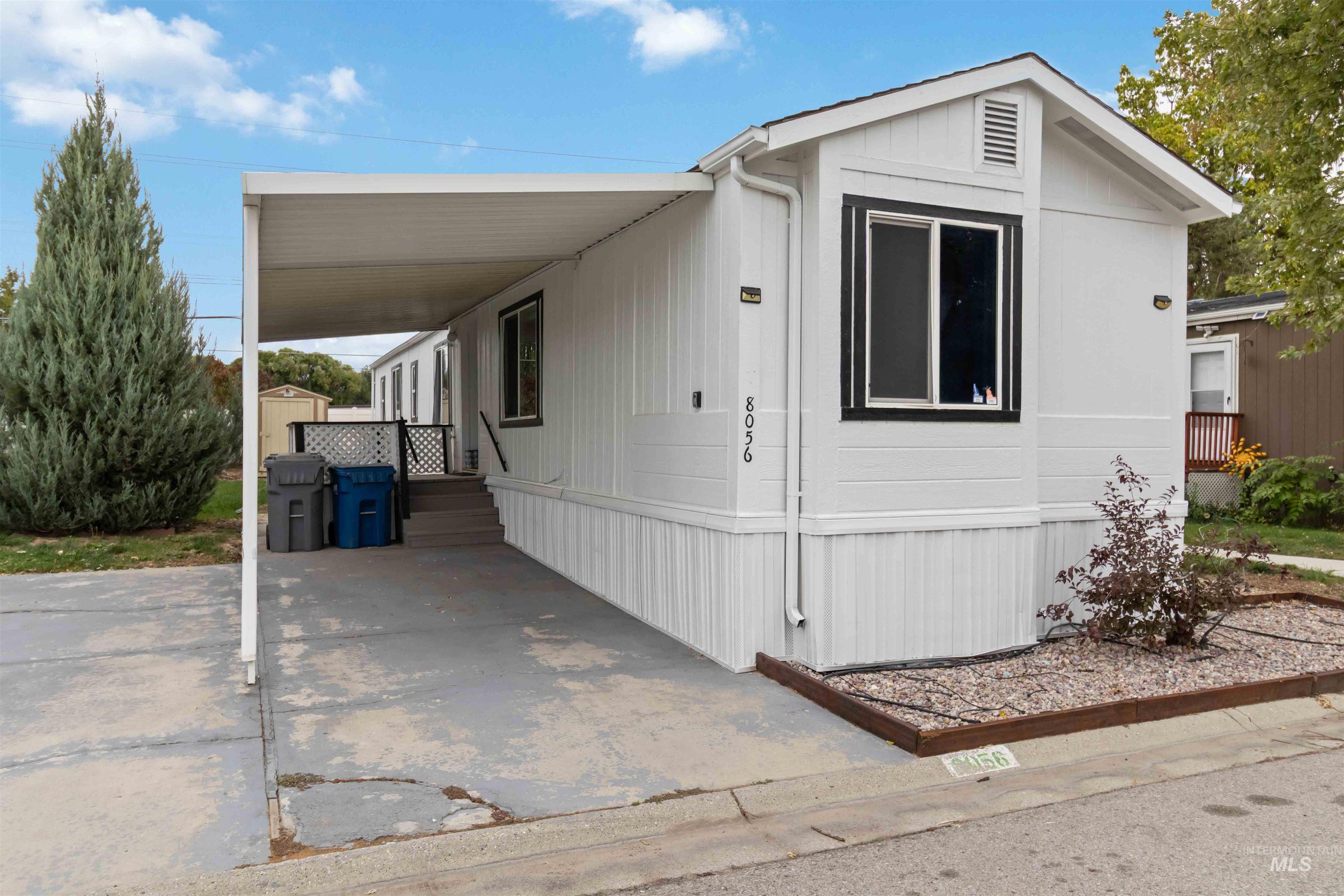 Manufactured / mobile home featuring an attached carport, covered porch, a shed, and driveway