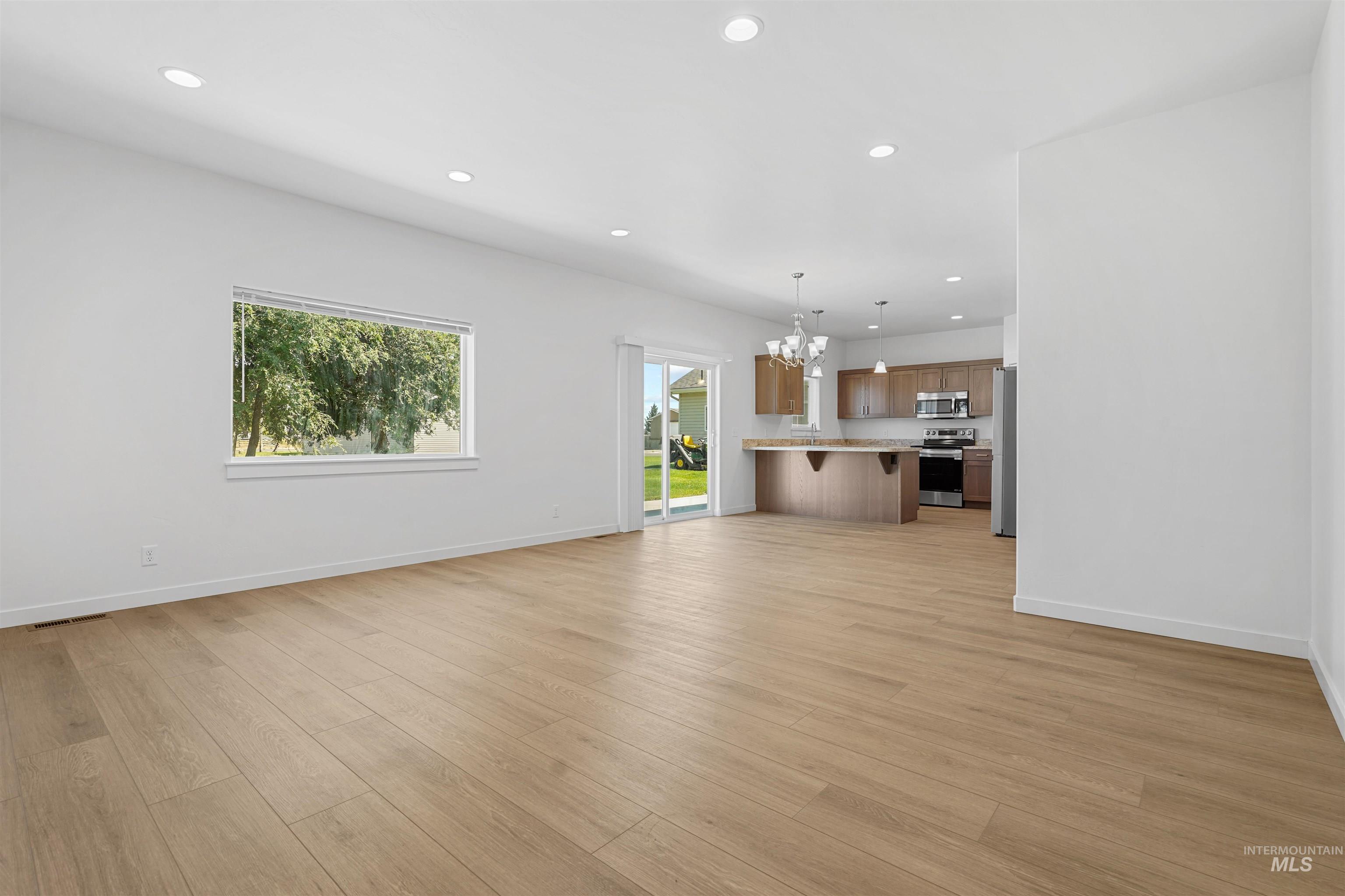 Unfurnished living room with recessed lighting, a chandelier, and light wood finished floors