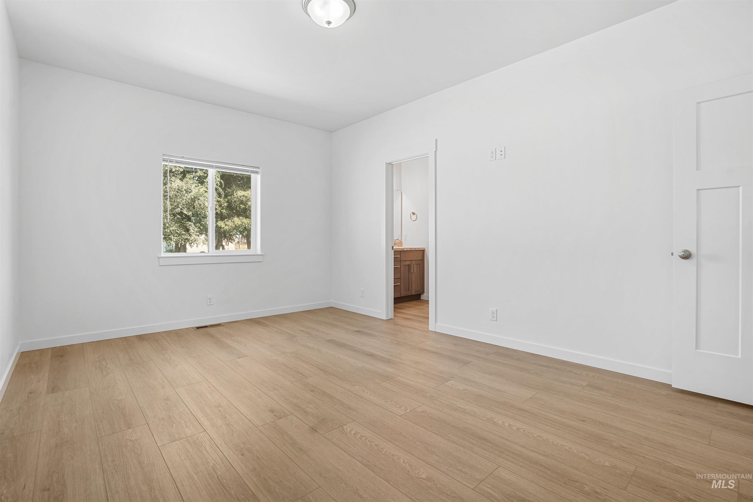 Unfurnished bedroom featuring ensuite bath and light wood finished floors