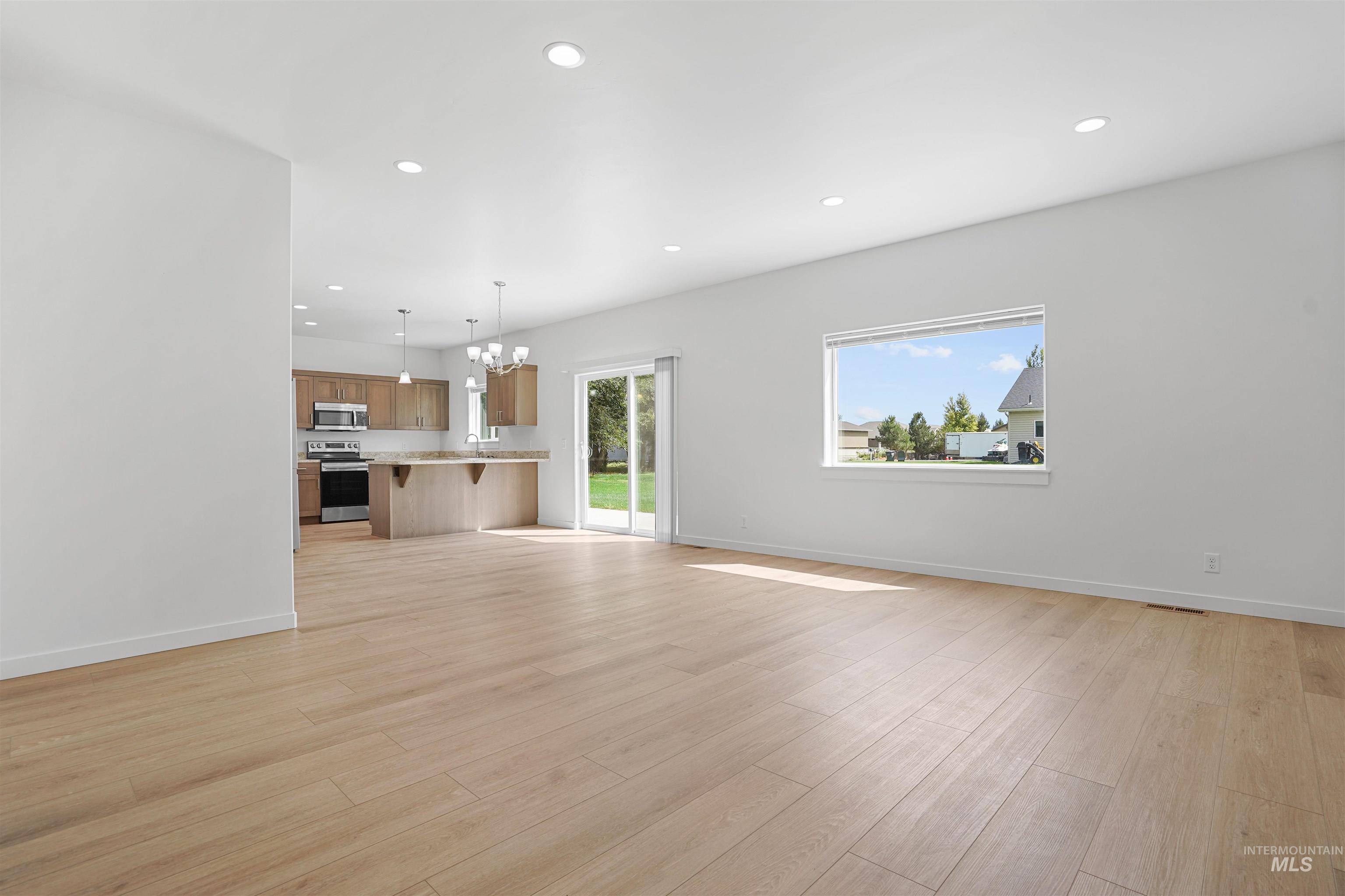 Unfurnished living room with recessed lighting, a chandelier, and light wood-type flooring