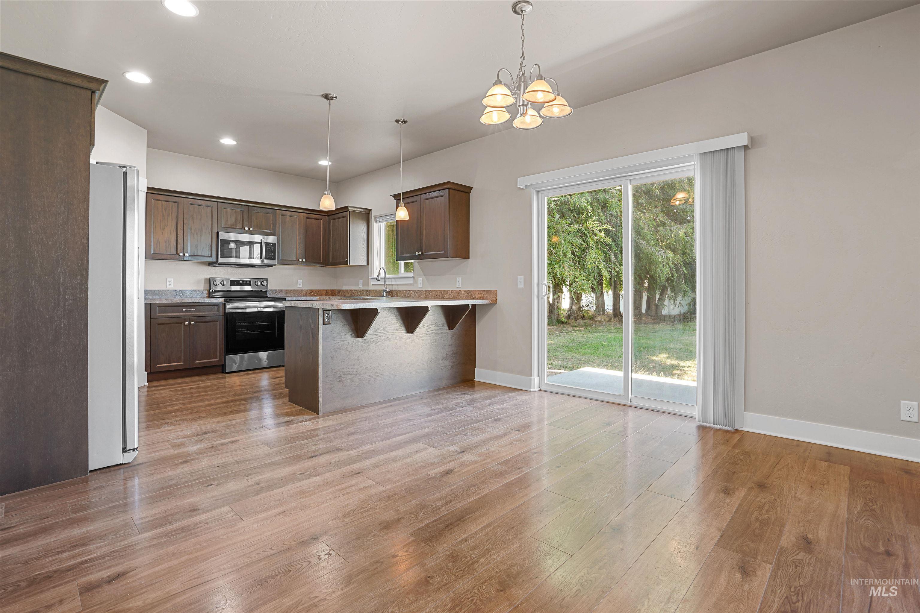 Kitchen featuring decorative light fixtures, stainless steel appliances, recessed lighting, a breakfast bar area, and light wood-type flooring