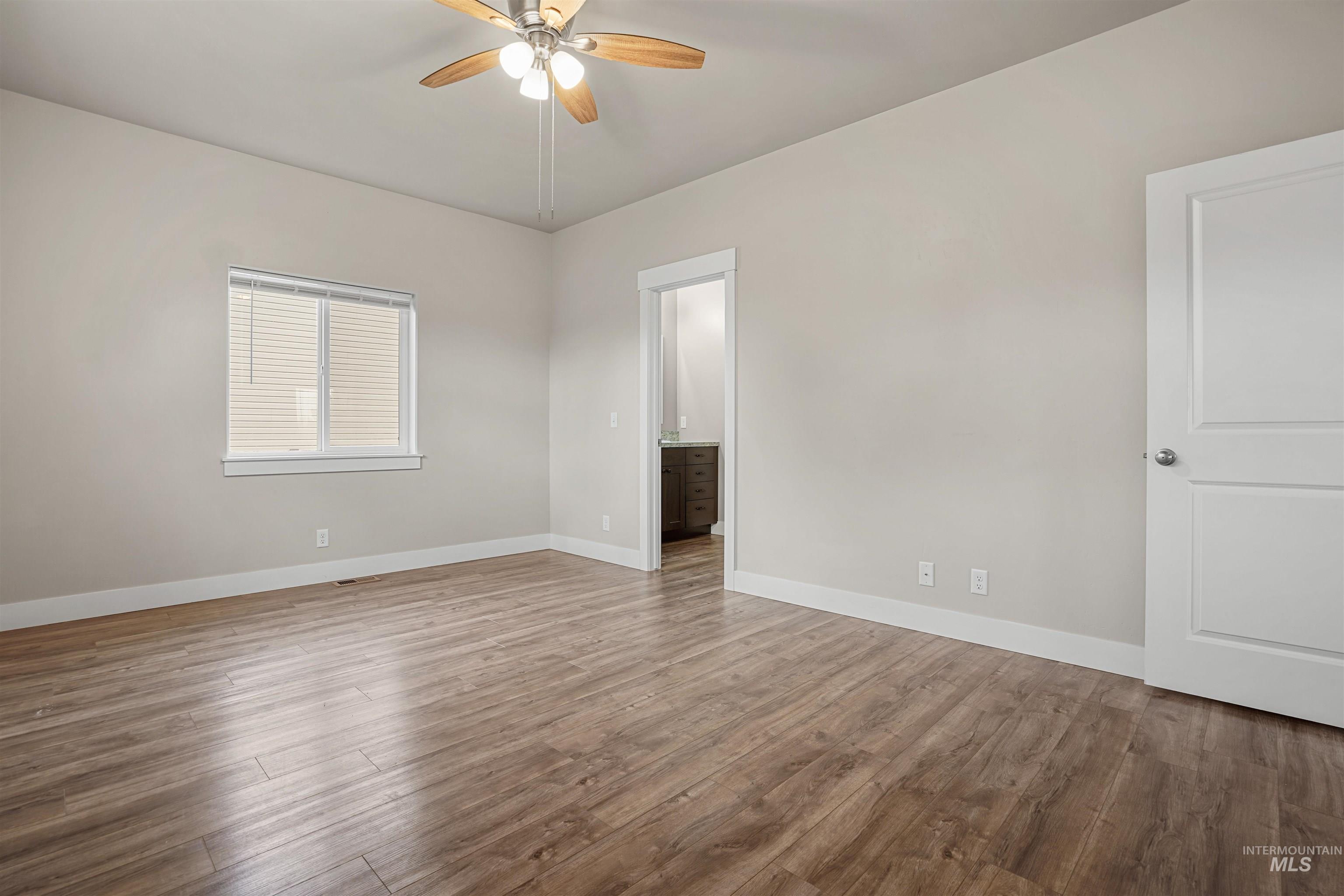 Empty room featuring light wood finished floors and a ceiling fan