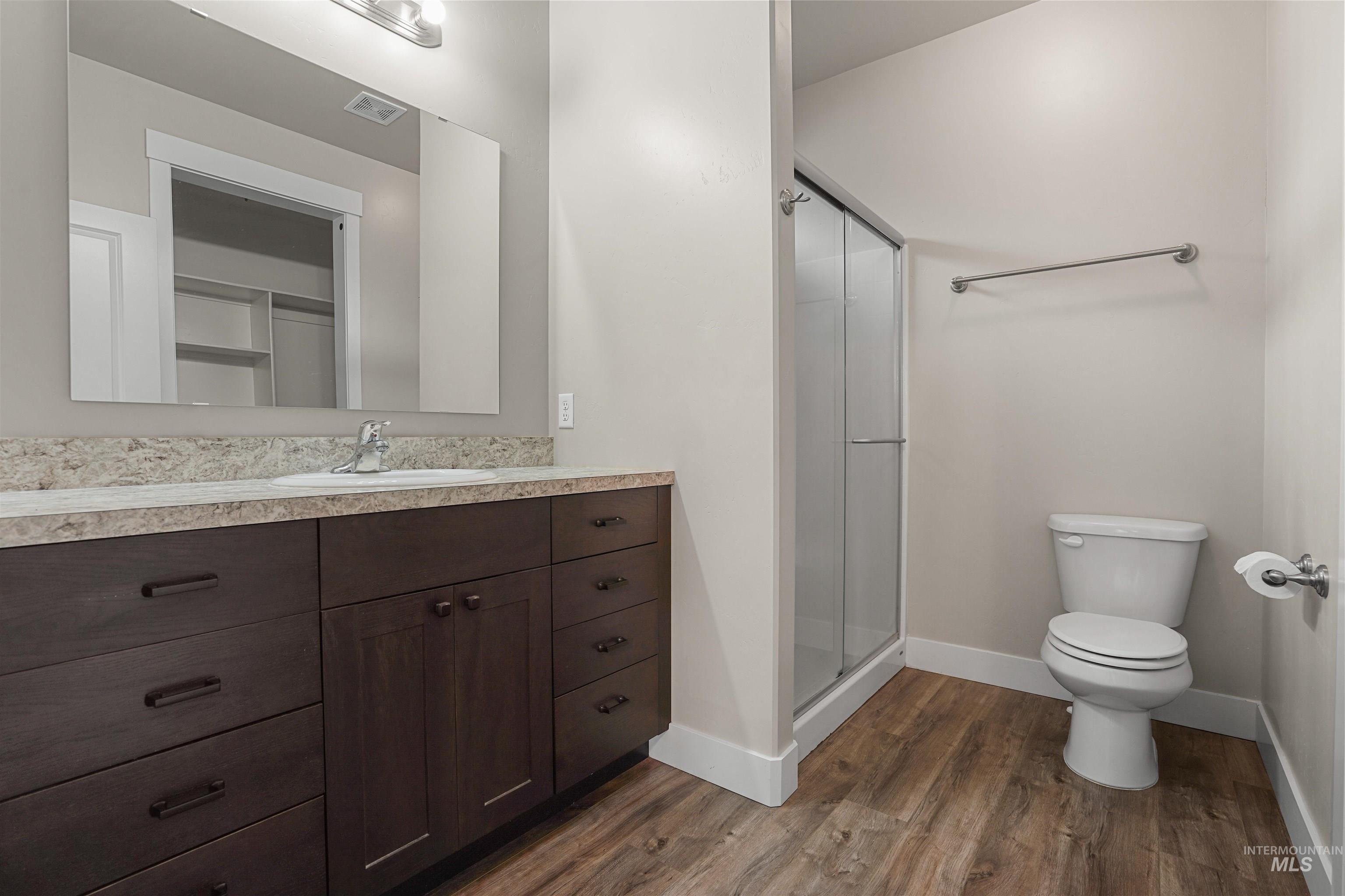 Bathroom featuring vanity, a stall shower, and dark wood-style flooring