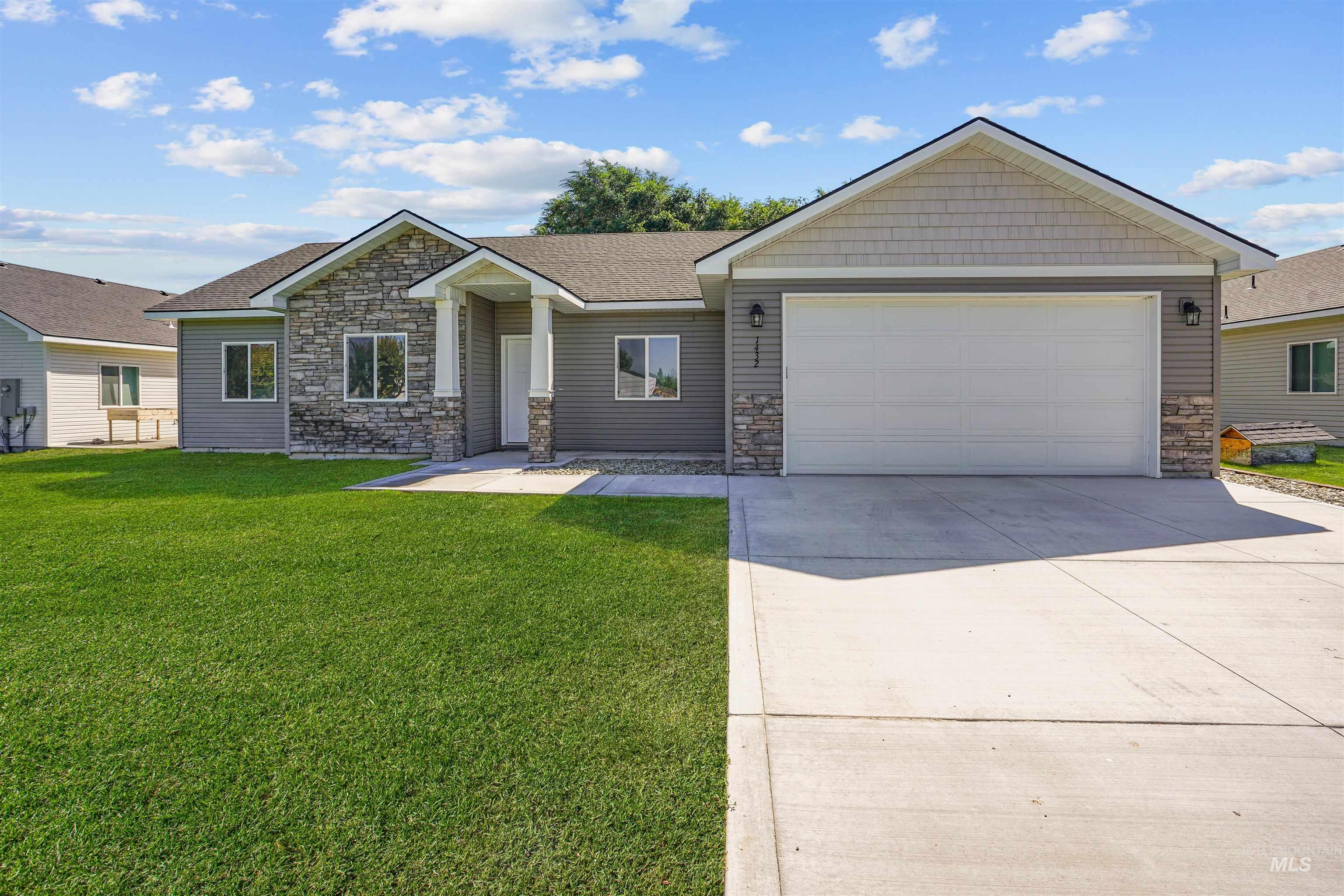 View of front of house featuring stone siding, a front yard, driveway, and a garage