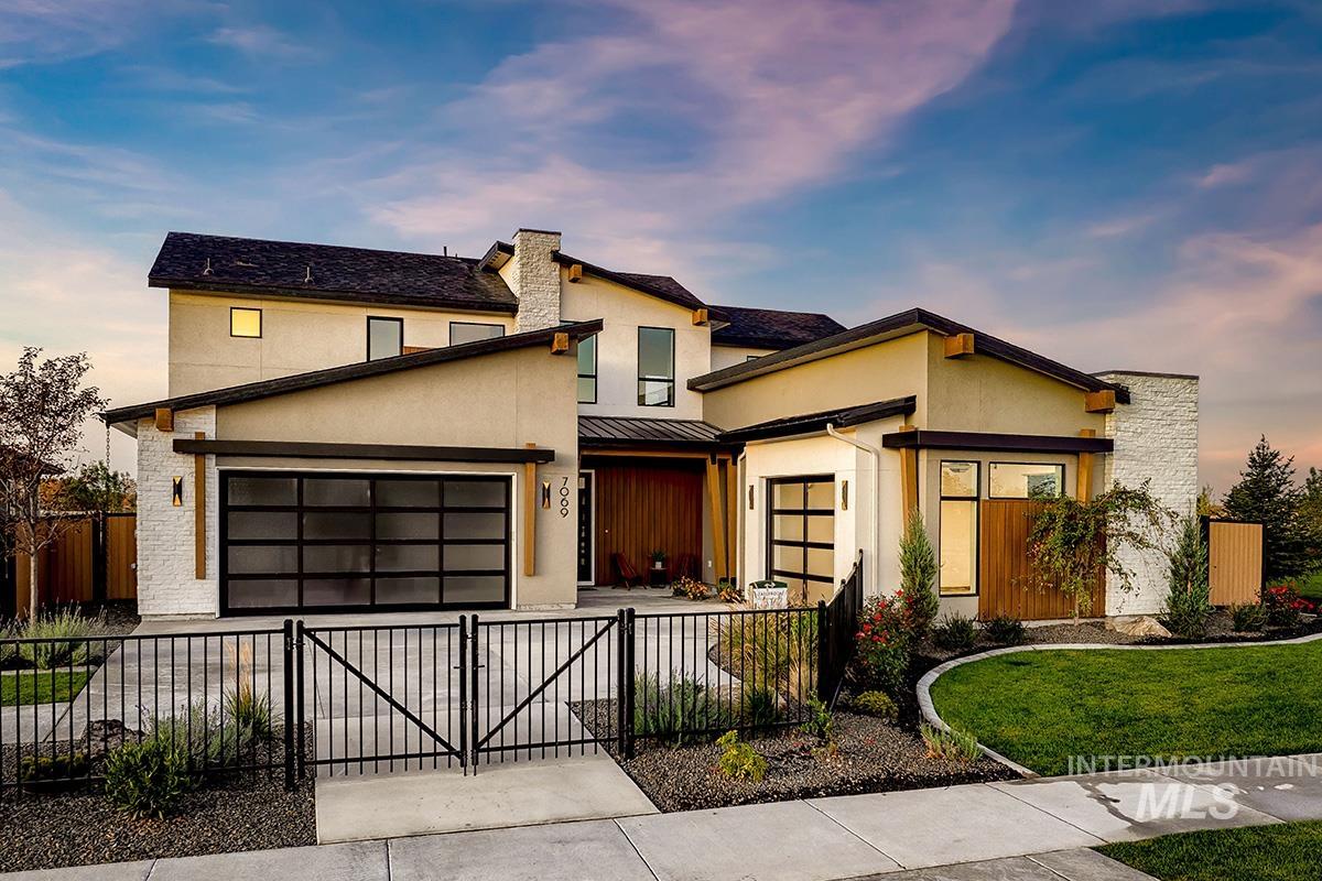 View of front of property with a fenced front yard, stucco siding, driveway, a metal roof, and a gate