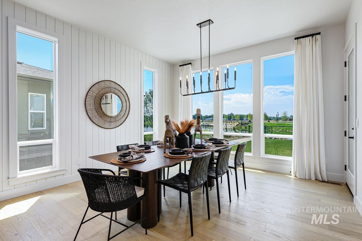 Dining room featuring light wood-style flooring, a chandelier, and wood walls