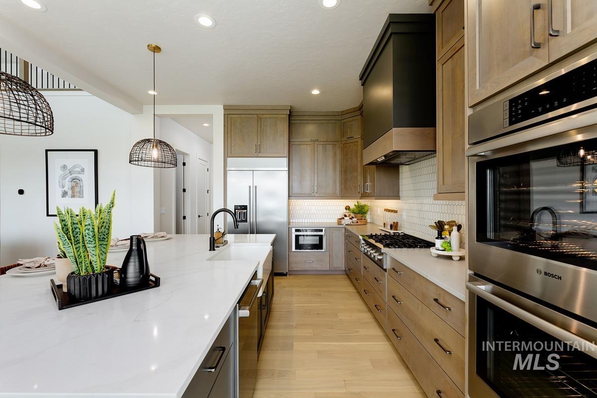 Kitchen featuring appliances with stainless steel finishes, light wood finished floors, backsplash, light stone countertops, and recessed lighting