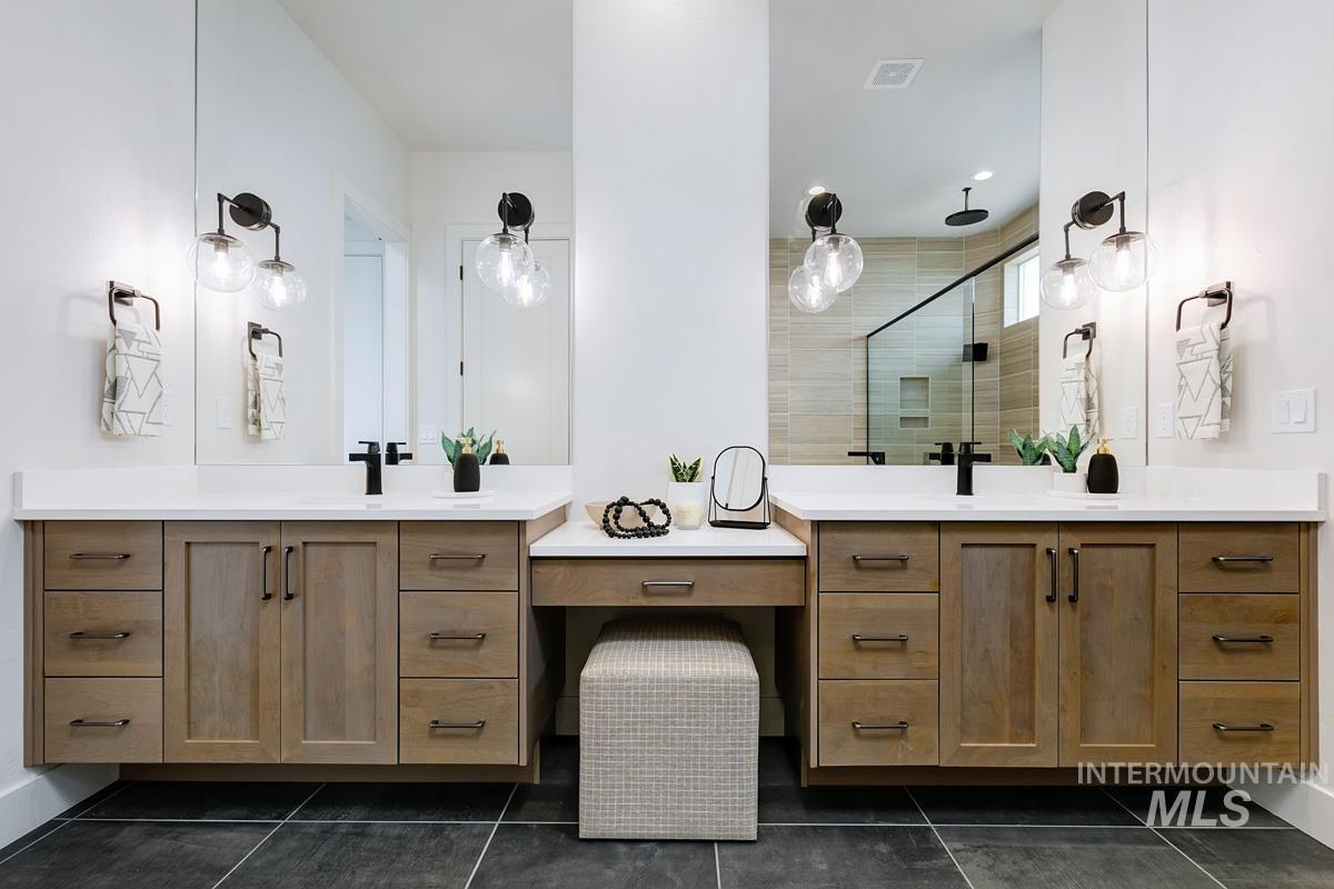 Bathroom with two vanities, a shower stall, and dark tile patterned flooring