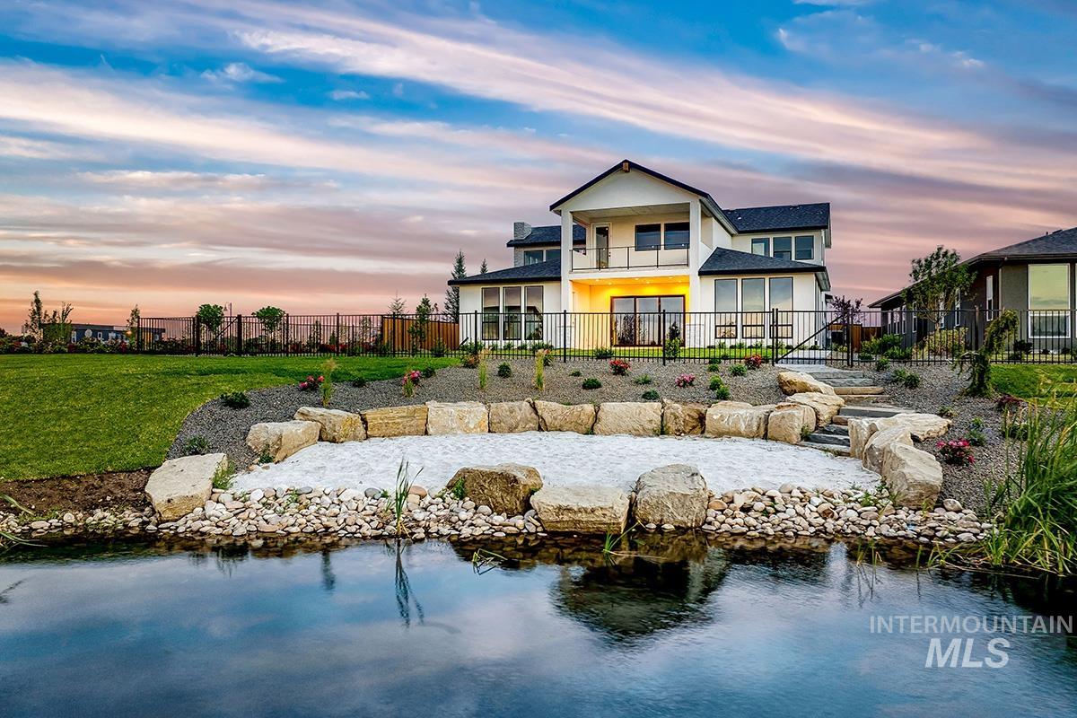 Back of house featuring a fenced backyard, a balcony, a water view, and a patio