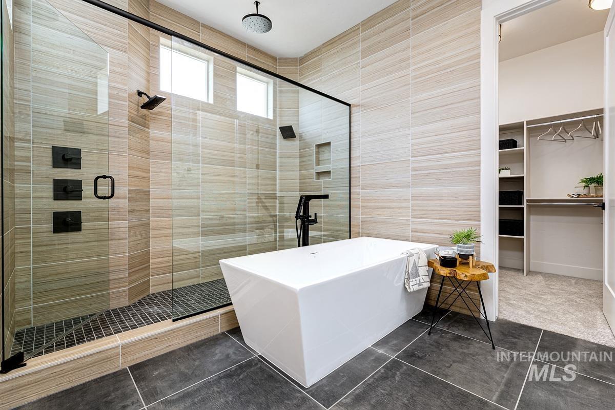 Bathroom with a stall shower, a walk in closet, a soaking tub, tile walls, and tile patterned floors