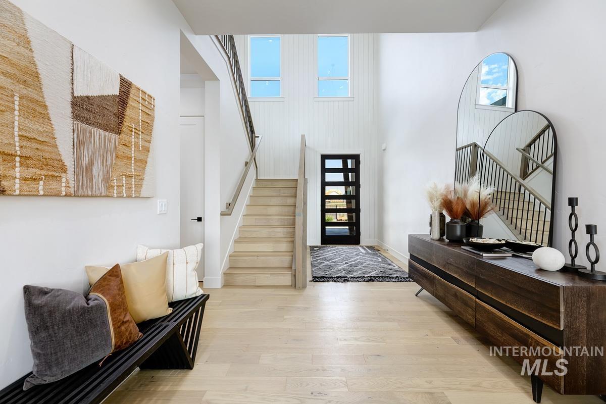 Entryway with stairway, wood finished floors, and a towering ceiling