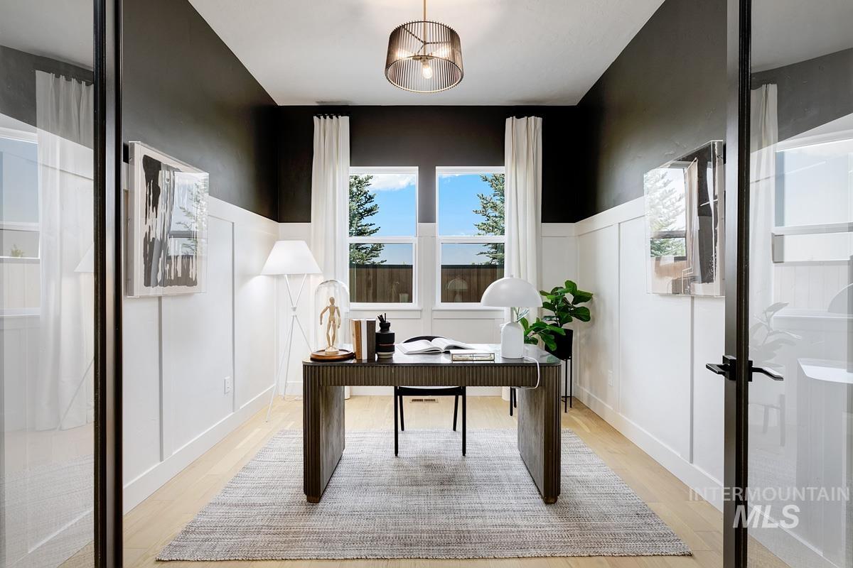 Office with light wood-style floors and a decorative wall